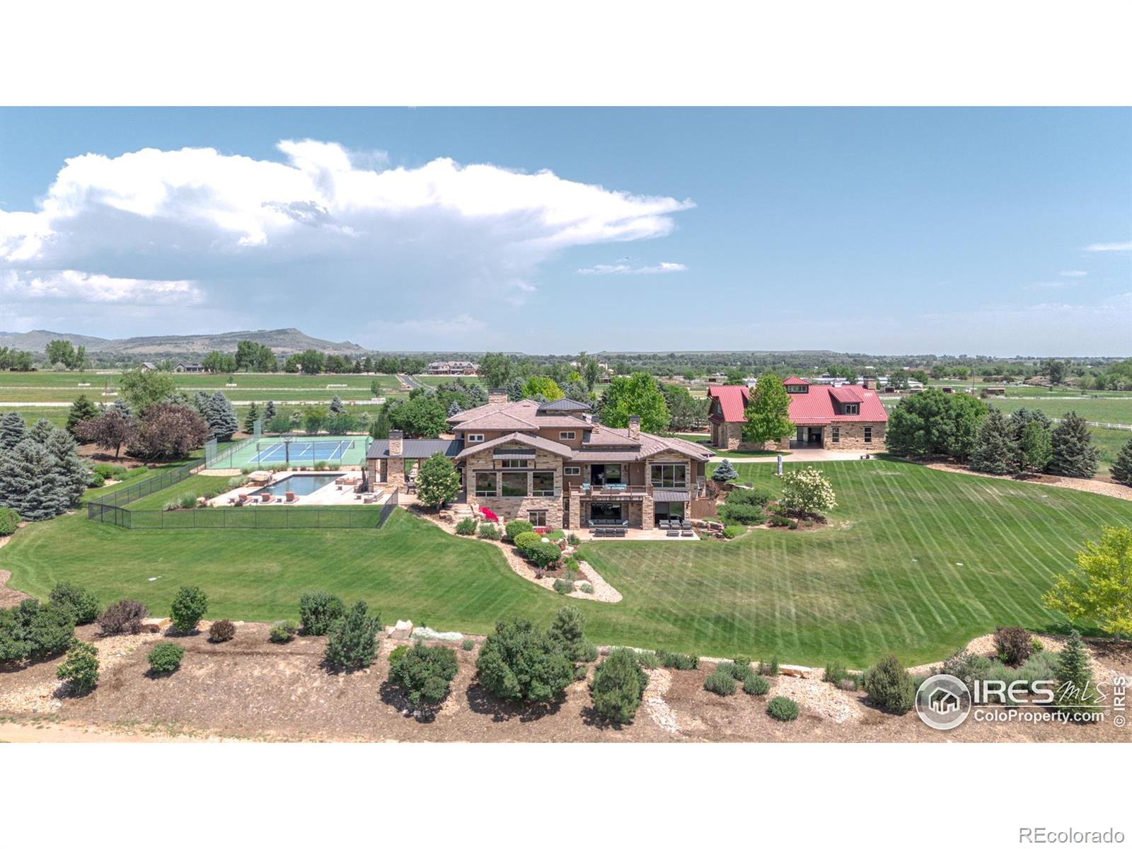 Set on 40 private acres with panoramic views of the Rocky Mountains, Longs Peak, and the Flatirons, 6880 Saint Vrain Road is a reimagined Colorado estate where privacy, natural beauty, and luxury converge. Gutted and remodeled in 2024, this exceptional compound includes a 10,801 SF main home, a 4,658 SF modern barn conversion, and a 4,950 SF second barn - plus a pool, spa, pond, waterfall, fire pit, tennis court, outdoor kitchen, multiple patios, and valuable water rights. Zoned for horses, the land offers ample space for future stables, pasture, or agricultural use. Inside, thoughtful design meets dramatic scale. Vaulted ceilings, wide-plank floors, exposed beams, and oversized windows create a warm yet elevated ambiance. A floor-to-ceiling stone fireplace anchors the great room, which flows into a chef's kitchen with Wolf and Miele appliances, a waterfall island, and walk-in butler's pantry. A breakfast nook captures iconic Flatirons views. The main level also includes a formal dining room, lounge, office, oversized four-car garage, pool equipment room, mudroom, and laundry with dual washer/dryers. Upstairs, the primary suite is a private retreat with a fireplace, balcony, soaking tub, and zero-entry steam shower. Three additional en-suite bedrooms and a second laundry room provide comfort and convenience. The walk-out lower level includes a wet bar, wine cellar, theater, gym, guest bedroom, and a one-bedroom suite with full kitchen, living room, bathroom, and patio. The converted barn features a commercial-grade kitchen, vaulted entertaining space, fireplace, bathroom, and oversized garage doors that open to the outdoors. The secondary barn provides soaring ceilings and flexible potential for equestrian use, a workshop, or creative pursuits. Just 20 minutes to Boulder, 10 minutes to Longmont, and 1 mile from the shops and restaurants of Hygiene.