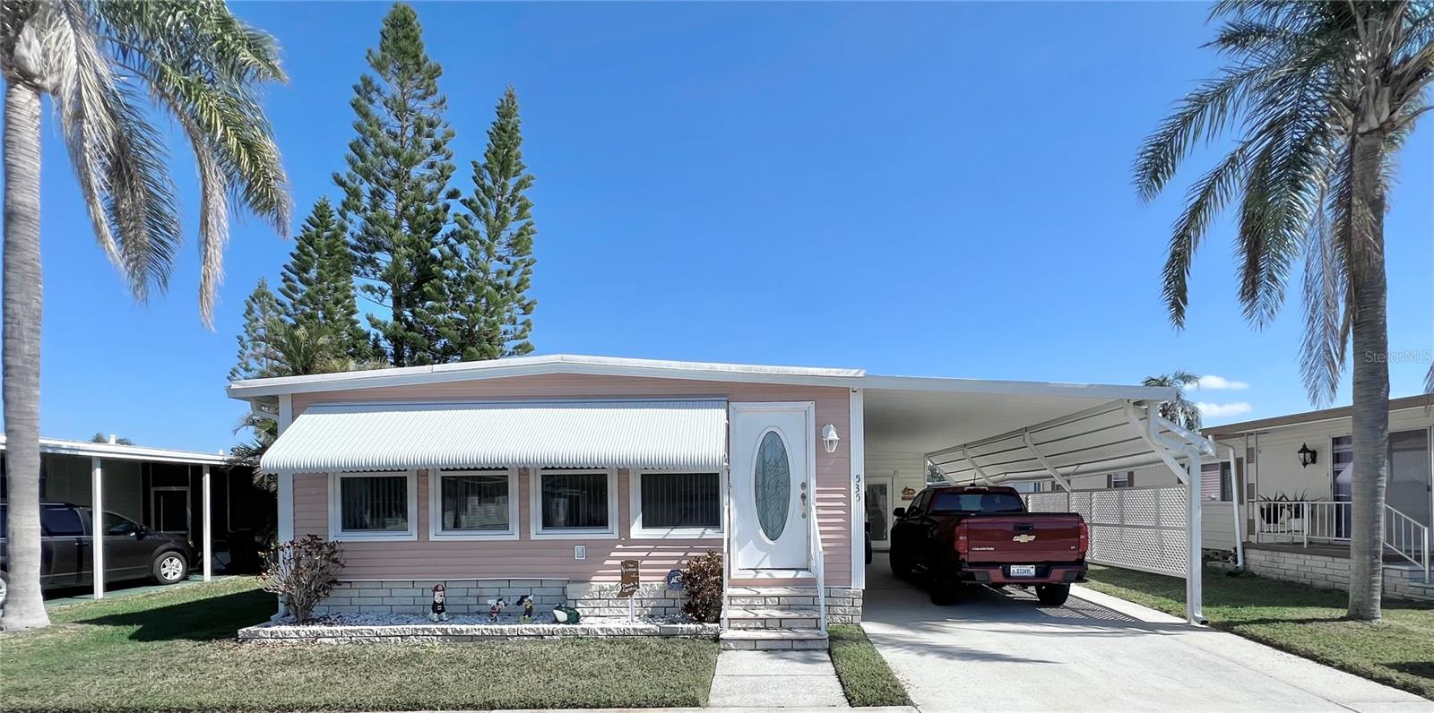 This meticulously maintained 2-bedroom, 2-bathroom home has been lovingly cared for by the same owners for 26 years, showcasing true pride of ownership. With many updates in the 1,584 square feet of usable living space (including two Florida rooms not counted in the stated heated and cooled 1,152 square footage), This home is both spacious and comfortable, as well as being sold fully furnished. Move right in!!!! The extended driveway fits two vehicles, and there's a convenient Florida room under the carport, complete with double French doors perfect for storing your golf cart when you're away for the summer or on vacation. The home features newer windows throughout and an awning over the front west-facing windows, ensuring the space remains cool and shaded. As you approach, the stunning NEW front door creates a welcoming entry. Step inside to the Florida room, thoughtfully transformed into a cozy TV/Den space with a dining table for those perfect sunset meals. The large living and dining areas are perfect for entertaining, with furniture that will impress and stay with the home. The kitchen has been updated with crisp white shaker cabinets, a cooktop stove with a vent hood, a wall oven, plus a small bar area to sit and conversate with the cook. All appliances, both large and small, along with cookware, are included. A broom closet could easily be converted into a pantry if desired. The dining area is modern with built-in storage and plenty of space. The home also boasts upgraded drywall and pristine flooring, with ceiling fans in every room. The spacious primary bedroom includes 4 closets, one of which is a walk-in, and the attached bathroom features a double vanity and fully tiled shower. The guest bedroom is conveniently located across the hall from the updated guest bathroom. This move-in ready home is perfect for anyone looking to enjoy the Florida lifestyle in a welcoming community. It’s located in Fairway Village, a premier 55+ manufactured home community, where a share is included in the list price for additional value. The community boasts an impressive 19,000 sq. ft. clubhouse with spaces for dances, bingo, card games, and more. There are two pools, jacuzzis, eight covered shuffleboard courts, and even a 9-hole par 3 golf course for a small fee. Ideally situated near major attractions, airports, and stunning beaches, Fairway Village offers the perfect balance of relaxation and convenience for both year-round living and seasonal stays. This is your chance to join a vibrant, active community and enjoy the best of your retirement years. Make your appointment today to see this wonderful home!