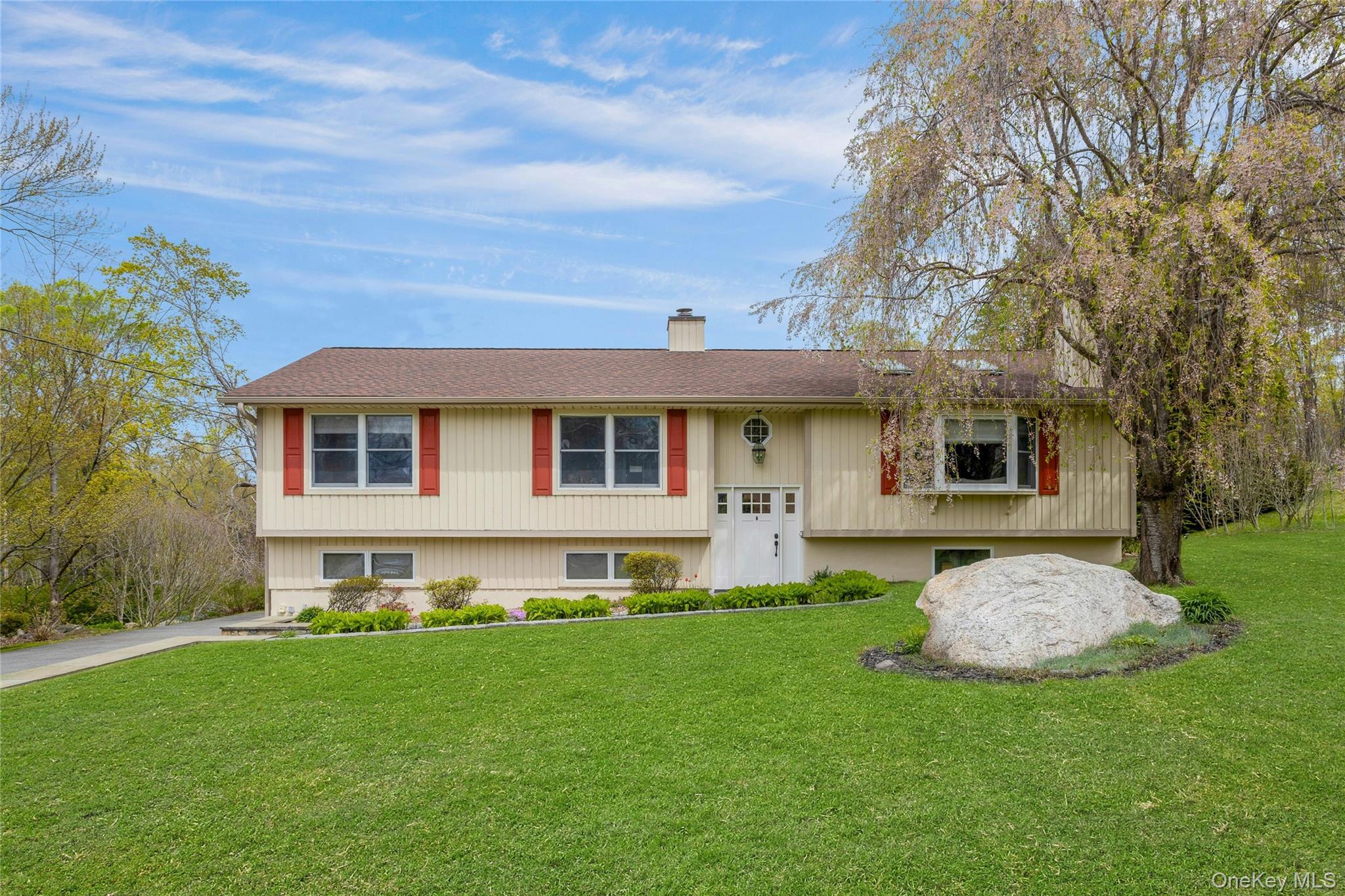 Experience modern living in this masterfully updated 3-bedroom, 3-bathroom home nestled in the sought-after Yorktown area — ideally positioned for those who love the outdoors, with easy access to local bike trails, Fahnestock State Park, and FDR State Park just minutes away. Set on a beautifully landscaped, park-like property that feels like a private oasis, this exceptional home blends natural surroundings with high-end interior finishes throughout.The brand-new Chef's kitchen anchors the main level with a massive center island, premium stainless steel appliances, chic glass-tiled backsplash, and custom wood cabinetry with glass accents — ideal for entertaining or everyday living. The living room features soaring vaulted ceilings and a warm wood-burning fireplace, while Velux rain-sensing electric skylights bathe the space in natural light. Cherry hardwood floors, custom blinds, and a freshly painted exterior complete the refined, move-in-ready presentation. The stunning primary suite offers a newly renovated en suite bath adorned with Carrara marble. The hall bathroom has also been beautifully renovated with a Rohl showerhead, and a third full bathroom on the lower level has been newly completed — ensuring every bath in the home reflects the same elevated standard. Practicality meets day-to-day living on the lower level, which offers a spacious office/den, large family room with direct garage access, and laundry area. Additional upgrades include a whole-house generator with a dedicated electrical panel, new garage doors, a newly installed interior oil tank, and a SimpliSafe security system with window and door sensors already in place. Outside, your private garden oasis and deck set the scene for summer entertaining, surrounded by lush landscaping that creates a true retreat-like setting. Located on a quiet, peaceful street just minutes from shopping, the Taconic Parkway, and Route 6, this home offers the perfect blend of suburban tranquility, outdoor lifestyle, and everyday convenience. Move right in and enjoy every custom detail!