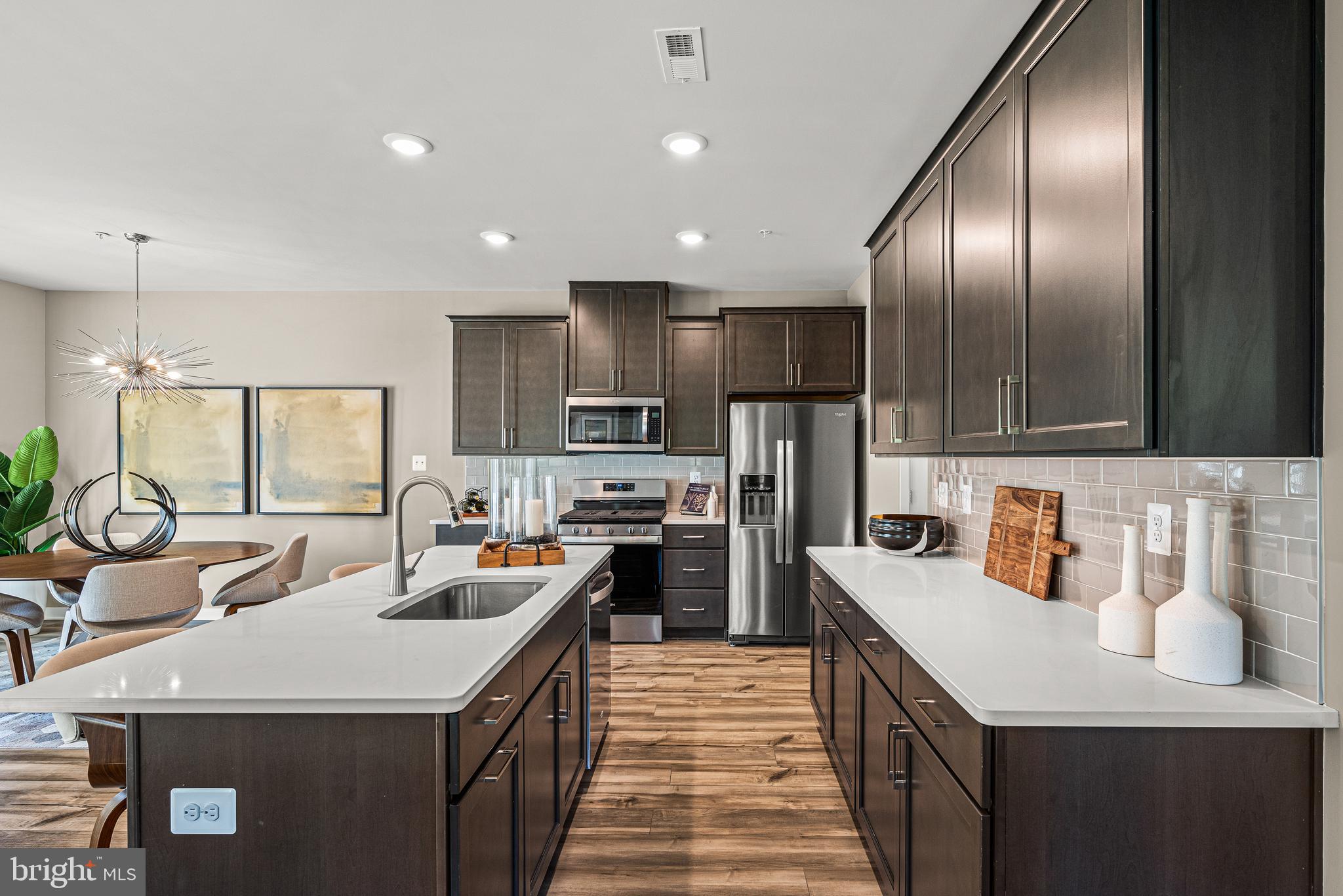 Built as Clover Mill's decorated model and never lived in, this end-of-row townhome carries the kind of details most homeowners spend years adding: custom architectural trim, designer wallpaper accents, statement lighting, and custom window treatments already in place. The kitchen anchors the main level with quartz counters and an oversized island, opening to a living area with wide plank flooring that flows to a low-maintenance deck. The primary suite offers a quiet upstairs retreat, and the finished lower level with powder room flexes as a gym, lounge, or second living space. Generous closets and storage throughout. Two-car garage plus driveway parking. The HOA covers walking trails, common areas, snow removal, trash, and recycling. Within the Downingtown East School District and STEM Academy boundary. Home does not include the furniture.