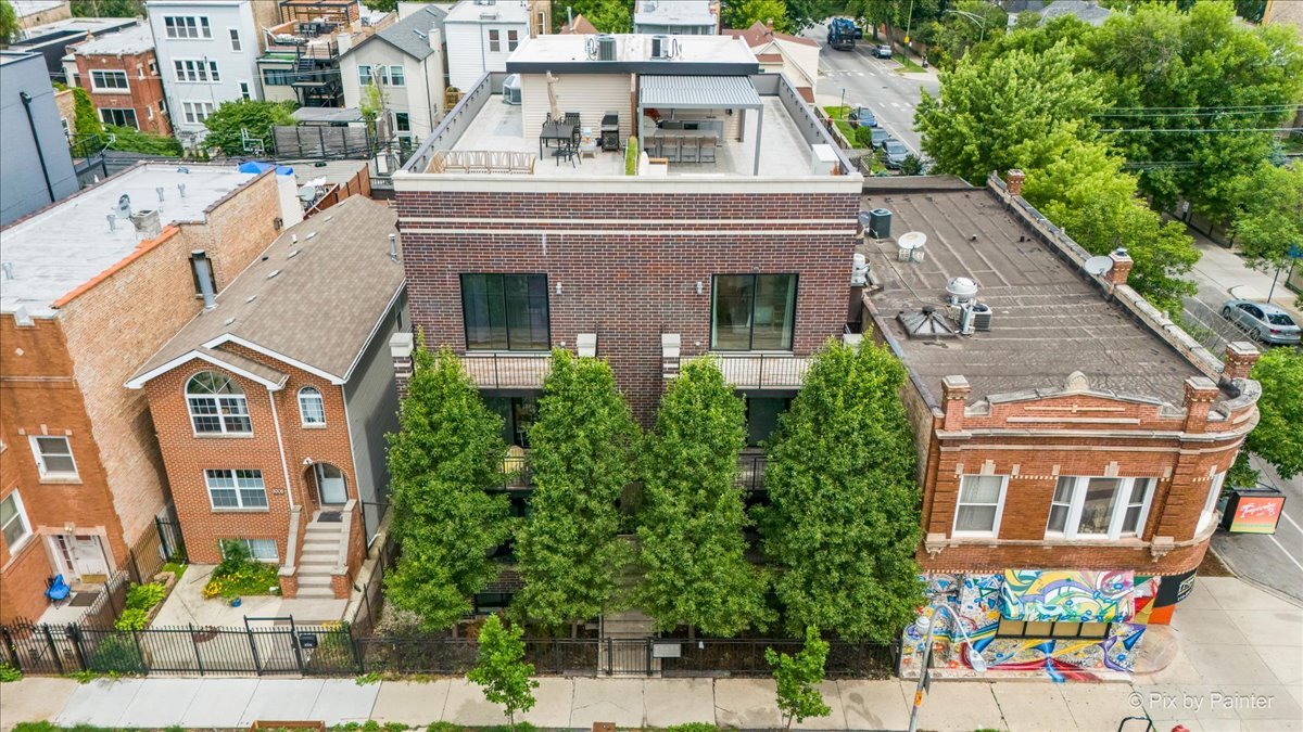 Incredible top-floor duplex-down penthouse located on a picturesque, tree-lined street in the heart of Logan Square, just a block from Palmer Square and the Blue Line. Built in 2016 and filled with natural light from its desirable southern exposure, this home lives like a townhome and offers multiple outdoor spaces, including a truly one-of-a-kind custom luxury rooftop deck with skyline views. The open-concept main level features a modern kitchen with soft-close flat-panel cabinetry, quartz countertops, white subway tile backsplash, and Bosch stainless appliances including a five-burner range with hood and French-door refrigerator. Adjacent to the kitchen is a spacious, full-width living and dining area with high ceilings, a built-in electric fireplace with accent wall, and a convenient powder room for guests. A side-by-side Whirlpool washer/dryer, additional pantry, and built-in storage are smartly tucked behind shaker-style doors.  The primary suite offers incredible light, a large walk-in closet with Closet Works systems, and an en-suite bath with a floating double vanity, quartz counters, oversized walk-in rain shower, and heated floors. The upper level also includes a bonus office/den and access to the private rooftop deck.  Designed for elevated entertaining and relaxation, this outdoor oasis includes a built-in Lynx gas grill, Kamado Joe smoker, Lynx beverage fridge, Summit kegerator, custom bar with storage, gas fire pit and separate enclosed doghouse storage area - plus power, gas, and water hookups along with a Pergola with custom lighting and adjustable louvers, a Huge sectional that wraps around the fire pit, and solar lighting lining the perimeter of the roof. The lower level offers two additional bedrooms, a full bathroom, a 154-bottle wine cooler, side-by-side beverage fridges, and direct access to a private rear deck off one of the bedrooms-perfect for guests or a quiet retreat. Recent improvements include a full roof replacement, gym-style flooring in the lower level, and additional structural and aesthetic upgrades throughout.    This well-maintained, boutique building fosters a friendly sense of community and includes garage parking, secure intercom entry, and an additional storage closet. With multiple decks, modern interiors, and unmatched outdoor space, this home is a rare find in a vibrant neighborhood-just steps from restaurants, shopping, and transit.