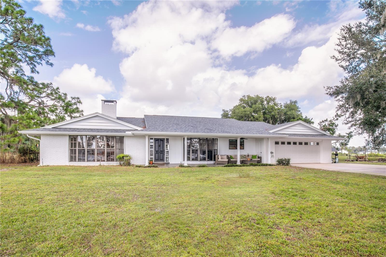 This beautiful private lakefront retreat offers over 300 feet of pristine shoreline and a private dock, creating the perfect setting to live your lakefront dream. Nestled on nearly two acres of property, this beautifully updated three-bedroom, two-bathroom home combines modern comfort with serene natural surroundings.

A charming front porch overlooks the water with unobstructed, south-facing views—ideal for savoring both sunrise and sunset across the lake. Inside, the open-concept single-story layout features tile floors throughout the main living areas and carpet in all three bedrooms. A floor-to-ceiling bay window off the kitchen floods the home with natural light and showcases the panoramic lake views, while sliding glass doors lead to a large, fenced backyard designed for seamless indoor-outdoor living.

The kitchen featuring a large island with bar seating, granite countertops, updated stainless steel appliances, a farmhouse sink, soft-close cabinetry, and a second prep sink—an entertainer’s dream. Large master suite and two additional oversized bedrooms and a large second bathroom offer ample space for family or guests. The home also includes a welcoming living room, a cozy family room with a wood-burning fireplace, and a separate laundry room for convenience.

Extensive updates and improvements make this home move-in ready and worry-free. A new roof was installed in October 2022, the property underwent a complete remodel in 2016—including a new kitchen layout, lighting, flooring, appliances, and fully renovated bathrooms—and a new well was added in November 2022. The home received new fencing and gate, freshly painted exterior and interior in November 2025. The beachfront was also cleared in 2025, ensuring direct and easy access to the lake.

Mature pine and oak trees surround the home, offering both shade and privacy, creating a true Florida oasis where nature and comfort come together perfectly