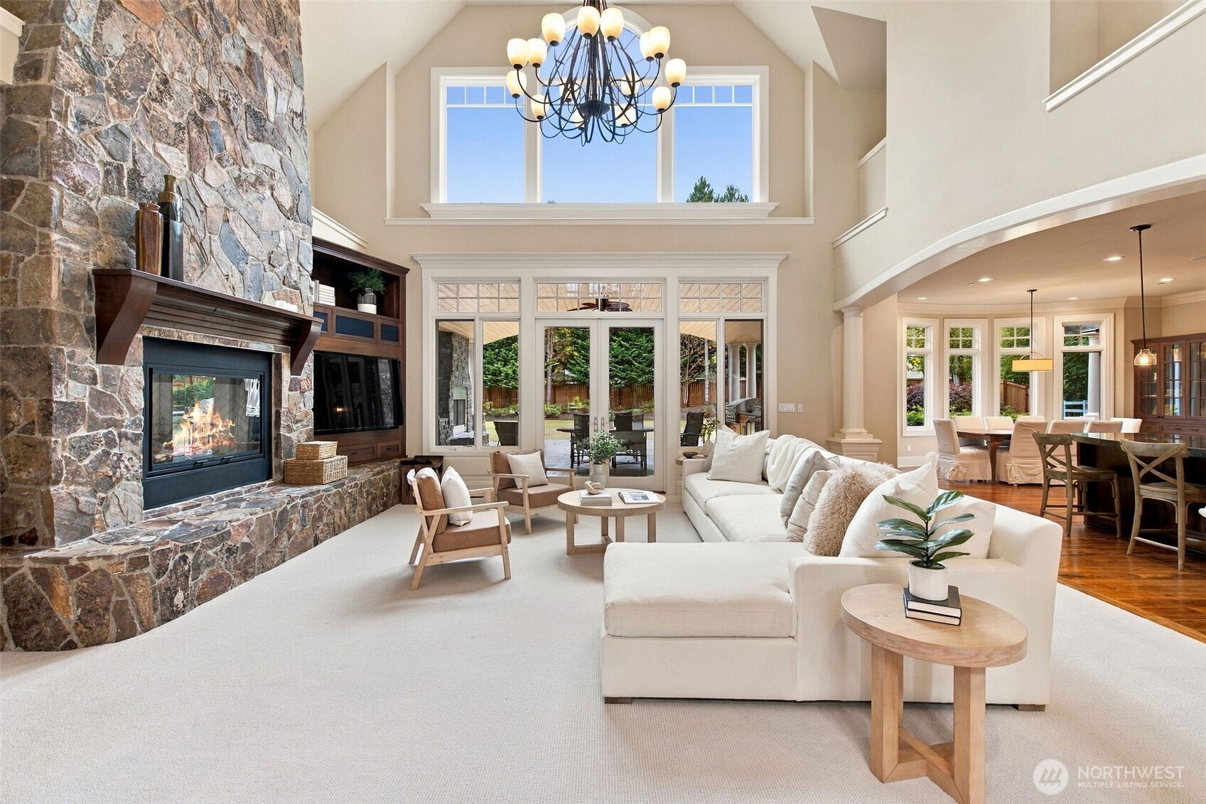 Expansive great room featuring soaring ceilings, a dramatic stone fireplace, abundant windows, and seamless connection to the outdoors.