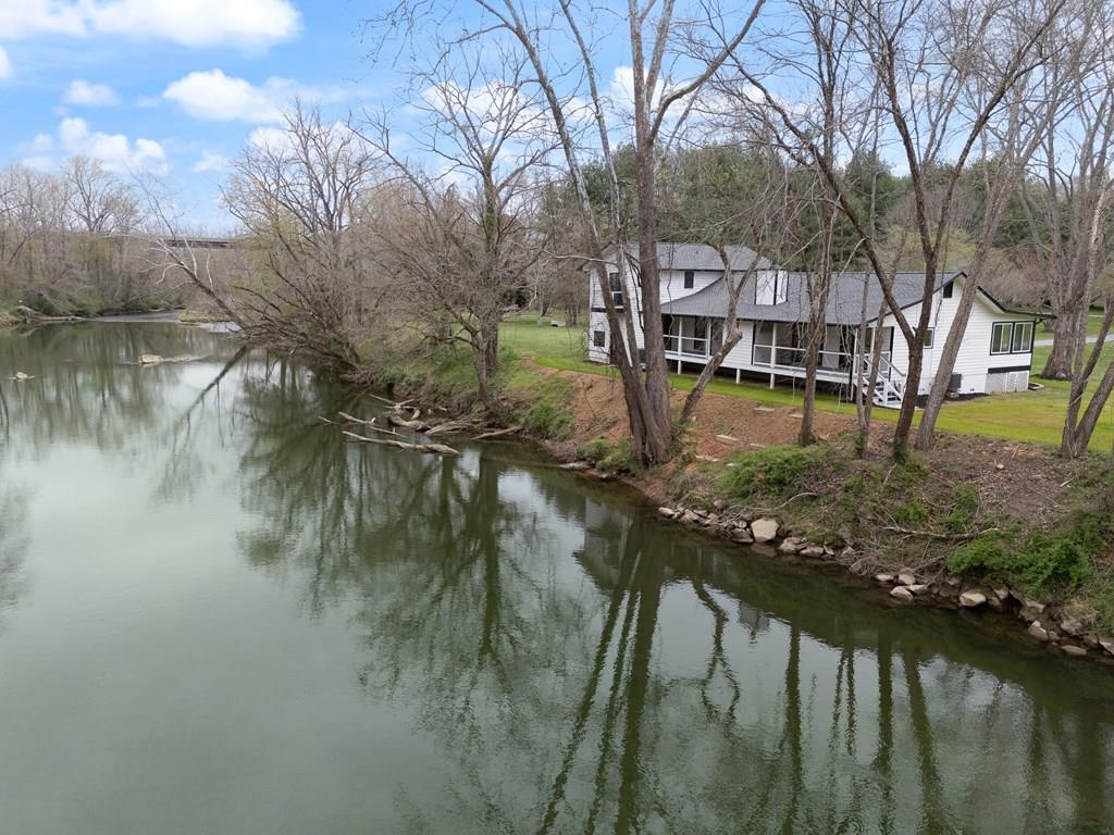 HIWASSEE RIVER FRONTAGE IN A QUITE PRIVATE 6 HOME DEVELOPMENT, THE SINGLE ENTRY PAVED ROAD IS PERFECT FOR CHILDREN AND ADULTS - THIS HARD TO FIND HOME RESTS 50' NEXT TO THE PEACEFUL FLOWING RIVER. LIKE BRAND NEW – FULLY RENOVATED WITHIN THE LAST 6 MONTHS!  This beautifully updated modern home has been completely transformed inside and out. The exterior features fresh paint, a brand-new roof with 30-year architectural shingles, new 6" gutters with leaf guards, along with 2 new HVAC / Heat Pump system for year-round comfort with new insulated vinyl-clad windows. Inside, you'll find fresh paint throughout, all-new flooring, and updated plumbing with modern fixtures in both the kitchen, bedrooms, and baths. The bright, open floor plan is filled with natural light and designed for easy living and entertaining. The spacious kitchen showcases new granite countertops and all-new SAMSUNG BESPOKE appliances, flowing seamlessly into the dining, living, and comfy family room. The family room, with its cozy stone wood-burning fireplace, provides the perfect spot to relax on cool mountain evenings. The main level offers 2 private primary master suites with updated baths, TWO additional bedrooms, and a full bath. A convenient laundry closet includes new SAMSUNG washer and dryer with added cabinets for storage. Step outside to enjoy the covered deck with peaceful river views. The attached TWO-car garage with new steel Cloplay insulated door with insulated windows with a lift master closer and features a separate living area above, complete with two bedrooms and a full bath with a walk-in shower—ideal for guests. Dual balconies offer both river views and front lawn perspectives. The property is complete with a well-maintained yard and fresh landscaping, making this home truly move-in ready.