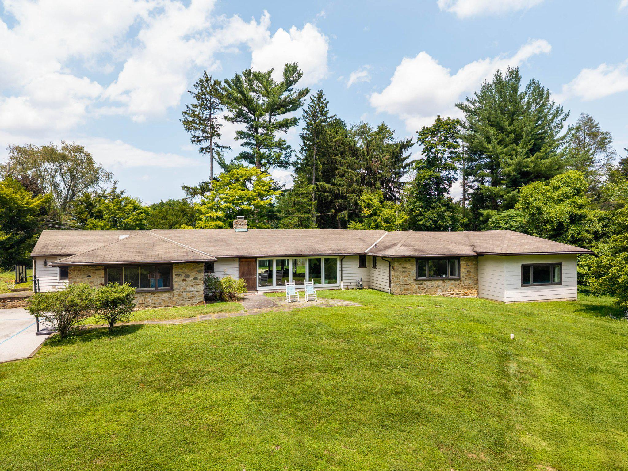 One-level living. Nearly an acre. Five bedrooms. Colonial Village.  Wayne, PA.Homes offering this combination of space, flexibility, and location rarely come to market.  Located in one of Upper Merion's original neighborhoods, Colonial Village is known for its mature trees, larger homesites, and convenient Wayne location.  Step inside to a light-filled family room where newer floor-to-ceiling windows at both the front and back of the home fill the space with natural light. Sliding glass doors open to the expansive, level backyard, making it easy to enjoy the private setting year-round.  The original bedroom wing offers two generously sized bedrooms with large closets, a full hall bath, and a third bedroom with its own en-suite bath, originally designed as the primary suite before the addition.  Just beyond, a two-step transition leads to the newer addition featuring a spacious primary suite with a custom walk-in closet, double vanity, soaking tub, and separate shower. An additional bedroom, ideal for guests, an in-law suite, or nursery, is connected to a private office or flex space with its own entrance to the side yard, creating a flexible layout for today's needs.  At the center of the home is the renovated kitchen with quartz countertops, stainless steel appliances, beverage refrigerators, generous prep space, and peninsula seating that naturally becomes the gathering place. The kitchen flows directly into the oversized dining room, making everyday meals and entertaining equally comfortable.  Just off the kitchen, a large den provides even more living space and is perfect as a playroom, media room, or casual family room.  Additional improvements include replacement windows (2018), two-zone HVAC, a new electric water heater (2026), and a waterproofed basement with a dehumidifier.