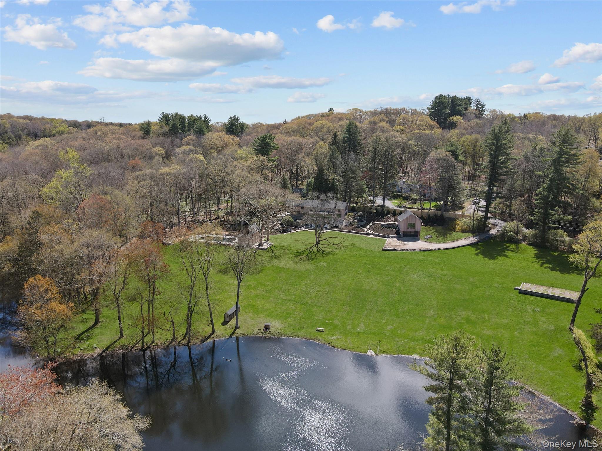 Behind private gates, nearly six acres of bucolic countryside unfold around a spring-fed lake — a setting that feels worlds away, yet sits just one hour from Manhattan.Gut-renovated to the studs and reimagined from the ground up, this Pound Ridge estate blends Mid-Century Modern design with original stone construction and hand-hewn beams — a rare marriage of architectural integrity and contemporary refinement. The result is a home that feels both timeless and entirely of the moment.The main residence offers four bedrooms and has sweeping water views that define the property. A detached guest studio with two-car garage provides flexible accommodation for visitors or staff, while the heated gunite pool and pool house — complete with full bath, wet bar, and huge fireplace — create an effortless setting for both quiet evenings and elevated entertaining. An additional detached two car garage rounds out the offering.Outside, the grounds have been as thoughtfully curated as the interiors: new landscaping, artisan stonework, full irrigation system, patios, and mature tree work frame the lake and connect seamlessly to the Pound Ridge Land Conservancy — a permanent buffer that ensures the privacy and natural beauty of this property endure.Truly turnkey. Completely one-of-a-kind.