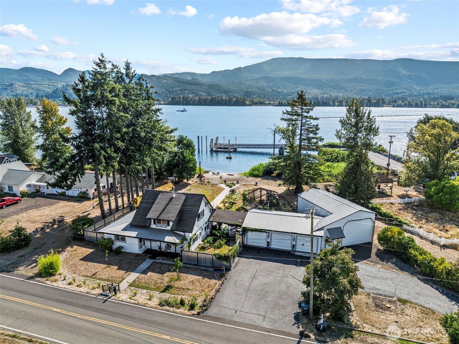 Don't miss your opportunity to own this sprawling 1 acre waterfront retreat with a private beach on the Columbia River! You will enjoy watching the "working river" VIEW from the property featuring local ferry, international ships, fishing, and wildlife views. This is a large 4bd 2ba home that has everything you need on the main floor.  Large primary en-suite w/ custom walk-in shower, open concept kitchen/dining with eat in kitchen, butlers pantry with french doors, and elegant living space with wood stove to cozy up to. Also a Ductless heat-pump for added efficiency. Upstairs you will find 3 more bedrooms, and a library/ TV area. This property has expansive grounds w/ a beautiful courtyard, conservatory, gardening shed/area, tool shed, chicken coop, and 5 shop/garage bays! Even a 19x40 Shop for RV/Trailer. Garages offer a possibility for home business. Property has a total of 4 driveway approaches. A paved wrap around driveway for everyday use, and back yard/beach access from either side of the property. The landscaping is impeccable and low maintenance. This Estate has so much to offer and is worth the time to come see it.