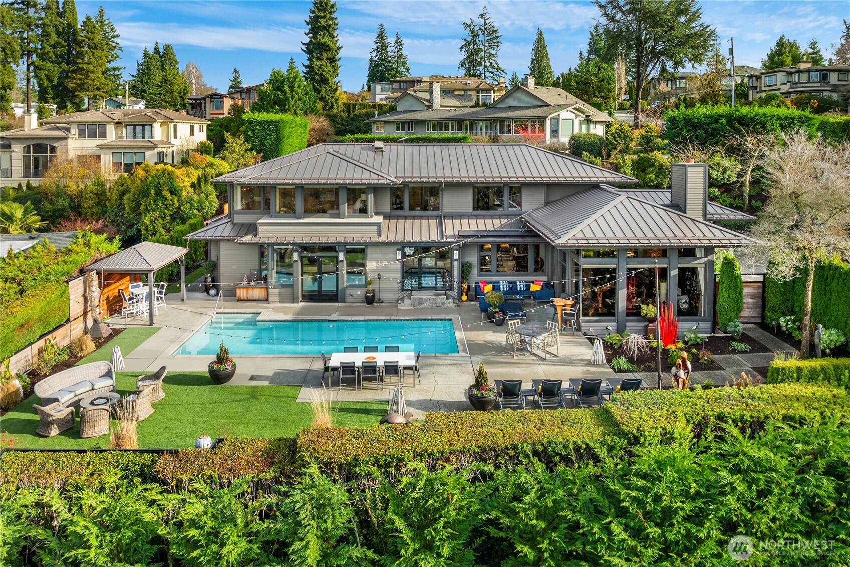 A one-of-a-kind Clyde Hill oasis where privacy, beauty, and effortless living come together. Set on a corner lot within a fully fenced gated property, this retreat offers a serene sense of seclusion and sweeping views across the water to Seattle. Moments from world class shopping, dining, Overlake Golf Course, parks, and quick access to I 90 and I 520, the lifestyle here is unmatched. Enjoy a saltwater pool, heated tile floors, electric shades, a temperature-controlled wine closet, a Zen studio with plumbing and sound, a metal roof, outdoor shower, generator, EV charging, and inviting outdoor living spaces. Many more thoughtful upgrades complete this rare find.