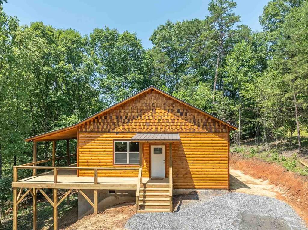 Spacious New Mountain Cabin – Thoughtfully Designed with Storage and Comfort in Mind. Tired of small cabins with no space to stretch out or store your gear? This brand-new mountain retreat offers everything you've been looking for—and more. Perfectly positioned between Murphy and Hayesville, you're just minutes from the John C. Campbell Folk School, Fires Creek Wilderness, and Lake Chatuge. Enjoy the beauty of the mountains without sacrificing convenience or comfort. Crafted with care and attention to detail, this newly constructed home includes a 1-year builder's warranty (expires 7/20/2026)—giving you peace of mind from day one. Located in a paved road development with only a short gravel driveway, this home offers ample parking, a turnaround space, and plenty of room for a boat, future storage shed, or workshop. Fiber internet recently ran in the development so it won't be long till you can get lightning fast speed. Step inside to a spacious and bright floor plan featuring vaulted ceilings, custom stone fireplace with handcrafted mantle, and abundant natural light throughout. Seamless Indoor/Outdoor Living - Double glass doors open onto a 10-foot-wide covered deck that spans the entire length of the cabin—perfect for enjoying the peaceful life among the trees.  Well-appointed kitchen with stainless steel appliances, granite countertops, and extensive workspace. A pantry adds charm and extra storage. Primary Suite - Roomy enough for a king-sized bed, with deck access from the double glass doors, a walk-in closet, and an en-suite featuring quartz countertops and a walk-in shower. Guest Bedroom - Filled with natural light, includes a walk-in closet and easy access to the hall bath with a tub/shower combo and quartz vanity. Bonus Features - 9-foot tongue-and-groove ceilings throughout, a laundry room with pocket doors and a separate utility/electrical room. This cabin is move-in ready, thoughtfully designed, and built to enjoy for years to come.
