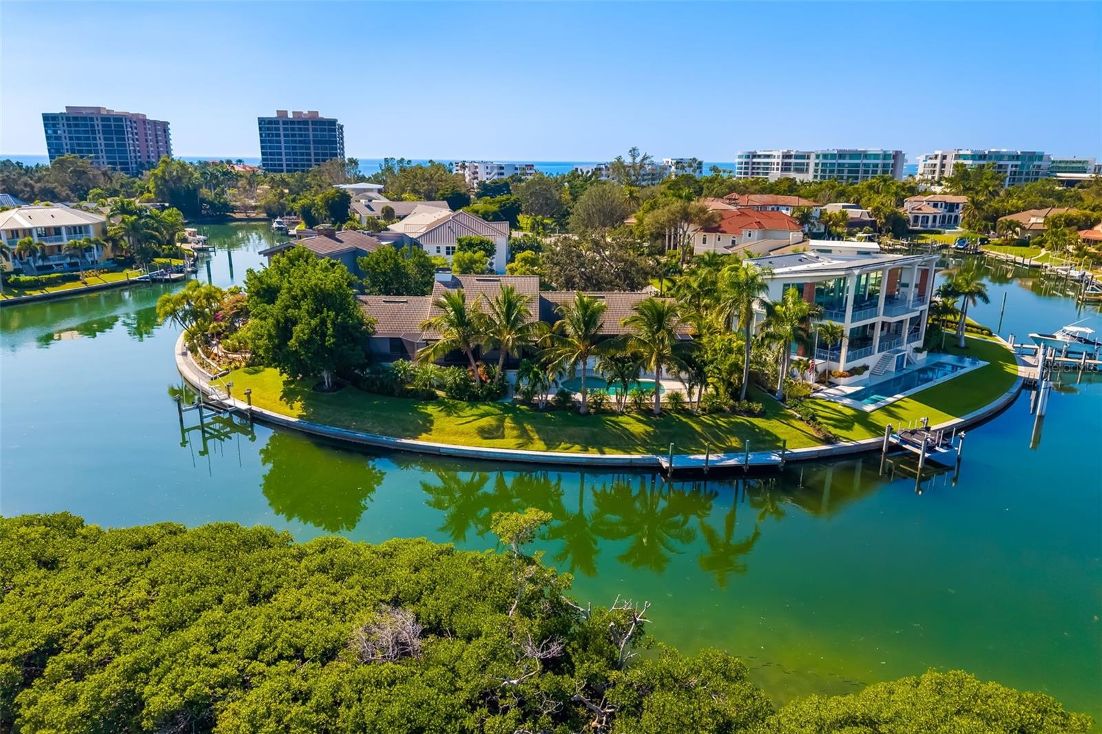 An exceedingly rare offering within the exclusive Bay Harbour enclave of Bay Isles on Longboat Key, this extraordinary peninsula estate delivers exceptional privacy, dramatic Sarasota Bay views, and direct boating access to both the Intracoastal Waterway and the Gulf of Mexico. Positioned at the end of a quiet cul-de-sac on a three-sided waterfront peninsula, the property features two private docks with water and electric, including one with a 15,000-lb lift designed for easy access. The Gulf is reachable through the nearby jetty with drawbridge, with an additional route via the John Ringling Bridge. The seawall was newly capped in 2020, and the pier deck and boat lift controls were replaced in 2025, ensuring superior waterfront infrastructure.Extensively rebuilt and structurally engineered, the residence is warm, refined, and filled with natural light, capturing sweeping bay views from nearly every room. The chef-inspired kitchen showcases custom rare wood cabinetry, an extended breakfast bar, a three-sink layout, double dishwashers, Sub-Zero refrigerator, Wolf warming drawer, standalone ice maker, and beautifully finished wood ceilings.The living and dining areas feature a custom jazz club floor and open seamlessly to a wraparound screened lanai, fully reconstructed with multilayer waterproof construction, a rich teak ceiling, and an open-sky section ideal for coastal breezes and stargazing. Multiple seating and dining areas create effortless indoor-outdoor living with uninterrupted water views.Outdoors, the pool area offers a private retreat surrounded by tropical landscaping and expansive travertine decking designed for both relaxation and entertaining. A custom palm-terrace garden enhances the tranquil ambiance along the east side of the deck.All bathrooms have been fully remodeled with premium finishes, floor-to-ceiling tilework, and frosted glass shower doors. The primary suite features an elegant, spa-like bath designed with refined materials.Additional upgrades include hurricane-rated windows and doors, 5-ton A/C units installed in 2024 and 2025, all-new plumbing, electrical, and HVAC ductwork, a whole-house water purification system, a full security camera system, and extensive structural improvements completed under engineering oversight. Exterior enhancements include landscape lighting, a resurfaced epoxy garage floor with mini-split A/C, and cell-foam insulation for efficiency.Residents of Bay Isles enjoy private Gulf beach access at the Bay Isles Beach Club, offering tiki huts, restrooms, BBQ areas, and gathering spaces. The gated community provides 24/7 security, community pools, and miles of shaded sidewalks ideal for walking and cycling.With its unrivaled peninsula setting, exceptional boating amenities, unmatched privacy, and sweeping water views at every turn, this estate represents one of Longboat Key’s most remarkable waterfront opportunities—an extraordinary residence defined by craftsmanship, luxury, and coastal elegance.