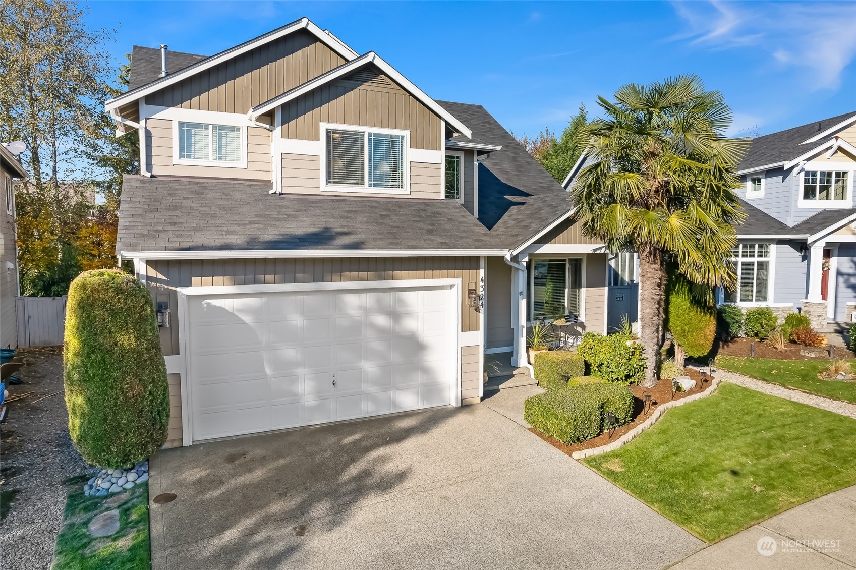 2 car garage with driveway parking, and a beautifully manicured front yard