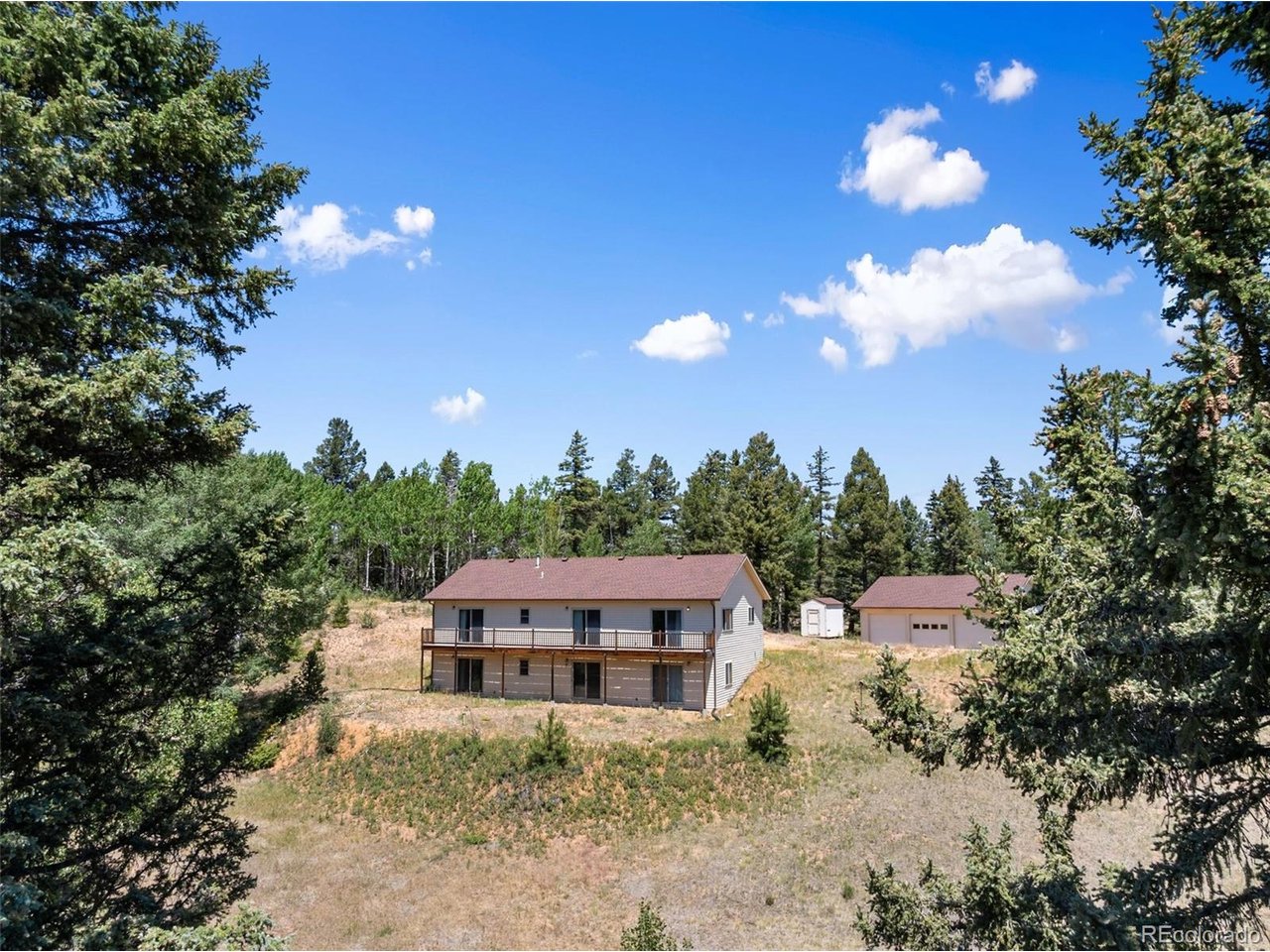 Discover the perfect balance of privacy and convenience on this remarkable 53+ acre property in Divide, Colorado.Surrounded by towering pines, open pasture, a live spring, abundant wildlife, and breathtaking mountain scenery, thispeaceful retreat offers room to roam while remaining just minutes from shopping, dining, outdoor recreation, andeveryday conveniences. The gated entrance leads to a secluded home set well off the road, providing exceptionalprivacy with no HOA restrictions. Designed to capture the surrounding beauty, the home features an open floor planfilled with natural light and inviting living spaces ideal for everyday living and entertaining. The spacious kitchen offerslots of cabinetry, generous counter space, a large center island with additional storage, and flows seamlessly into thedining and living areas. The main level includes three bedrooms, including a private primary suite, while the finishedwalkout basement provides a spacious family room, three versatile bonus rooms, and an additional bath, offeringendless flexibility for guests, a home office, hobbies, fitness space, or storage. Radiant in-floor heat, passive solardesign, skylights, and a backup boiler add year-round comfort and efficiency. Outside, you'll find a detached five-cargarage and a storage shed, providing ample space for vehicles, equipment, and recreational toys. The fenced acreage isideal for horses, cattle, or simply enjoying the freedom of wide-open mountain living. Whether you're searching for afull-time residence, a mountain getaway, or a property with room to expand, this exceptional offering combines privacy,functionality, and the Colorado lifestyle you've been dreaming of. Rarely does a property offer this much land,versatility, and seclusion while remaining conveniently close to town.