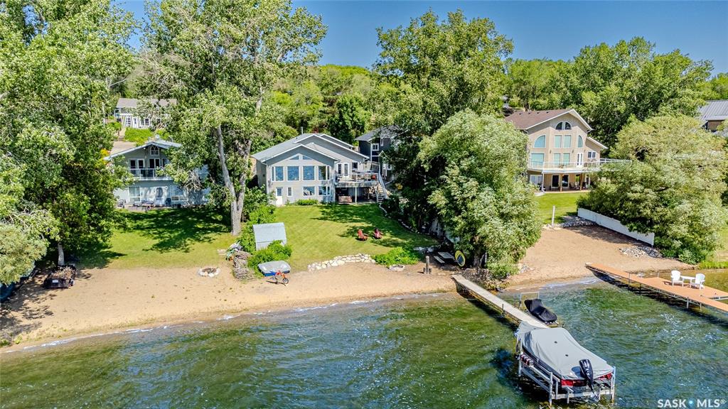 Welcome to your year-round waterfront retreat in the village of Thode on Blackstrap Lake, just 25 minutes from Saskatoon! This beautifully renovated walkout bungalow was originally built in 1972 and extensively upgraded in 2002, including a full roof replacement (singles since replaced in 2024), new plumbing and electrical, double attached garage and a spacious addition with ICF foundation. Inside, you’ll find 13’ vaulted ceilings, a full wall of windows with unobstructed lake views, hardwood flooring, and an open-concept layout with a gas fireplace, dining area, and a kitchen featuring quartz countertops, stainless steel appliances (induction oven), tile backsplash, a double undermount sink, and an eat-up island with central vac kickplate. The main floor has two bedrooms, including a stunning primary suite with lake views and vaulted ceilings, a walk-in closet, 3-piece ensuite, and direct access to a large deck with hot tub, natural gas BBQ hookup and lots of room to share a meal, enjoy your morning coffee or just relax and enjoy the beautiful lake views. An office completes the main level (with lake views!) that could easily be converted into a fifth bedroom by reversing one closet from the other bedroom, making this a great family home. The lower level offers two more bedrooms (one doubling as a family room), a partially finished rec space that could be used as a home theatre, games area, or suite conversion. Off the back you'll find a beautifully landscaped yard with mature trees, perennials, and your own private beach! This is a rare opportunity to own a move-in-ready lakefront home with beautiful lake views and year-round appeal with quick access to Saskatoon. Contact your Realtor® today to book a private showing!