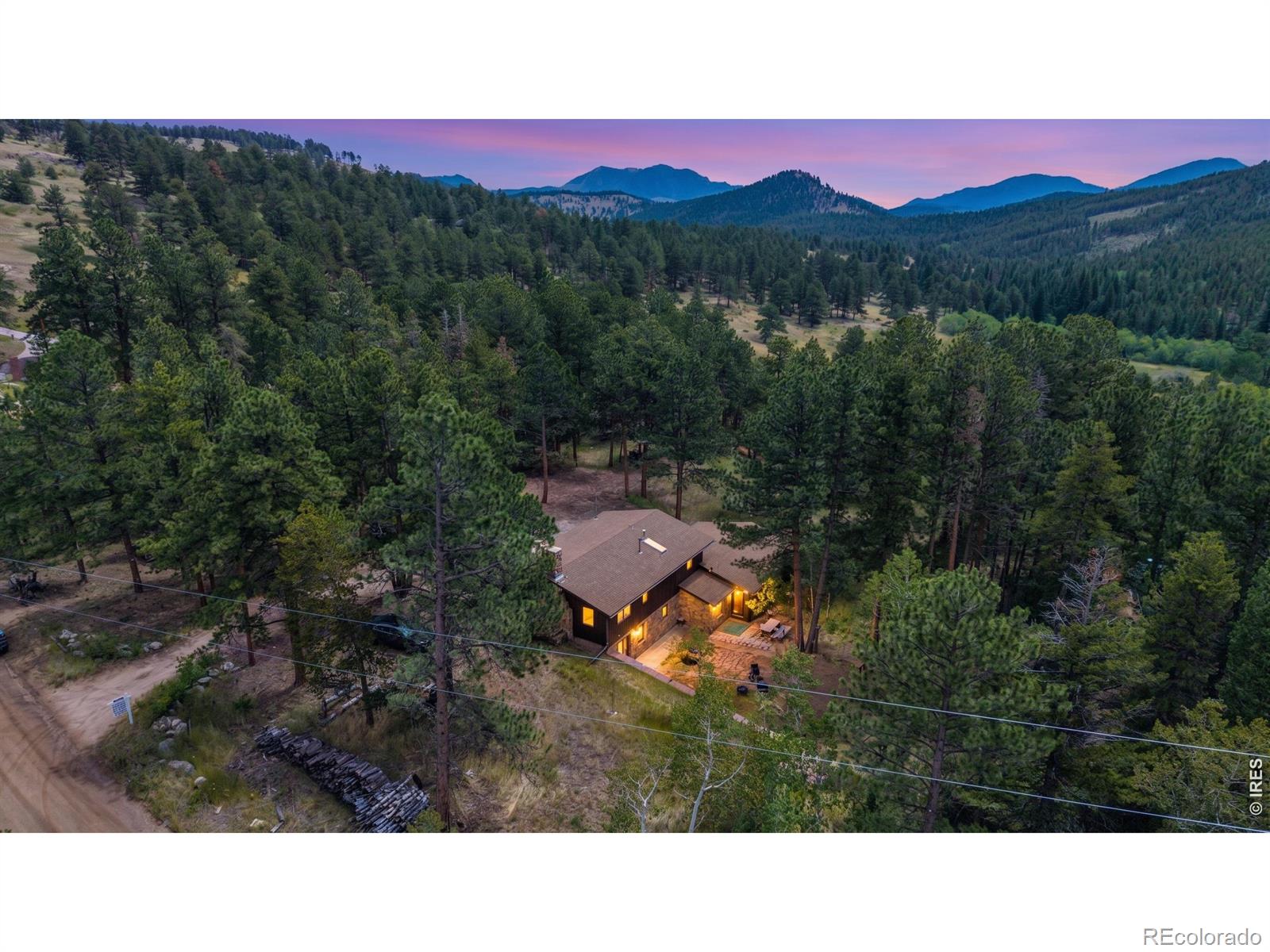 Seeking the serenity of a peaceful mountain retreat but not willing to part with your perfectly manicured backyard oasis? - Check this out! This 3 bed, 2 bath rustic mountain home with a dedicated office and 2-car garage sits on an acre of beautiful mountain land opening to a scenic valley. On the lower level, the home sports a kitchen with new appliances, a pull up island AND peninsula, which flows directly into a warm and inviting great room anchored by a central wood-burning fireplace that really gets the job done in winter. From the dining area, a large glass slider takes you out to the generous, grassed yard with dining and grilling areas, a beautiful swing set for adults and kids as well adorned by string lights overhead. Upstairs there are 2 guest bedrooms with closets and a third room with built-in shelving that's currently used as an office. The largest room upstairs is a massive primary with its own fireplace and dual closets. It's connected to the shared full-bath with dual vanities and an amazing WATERFALL shower/tub combo plucked right from your favorite hot springs or spa. The lower level also includes a 3/4 bathroom as well as ample storage and utility space, with included laundry set, off the oversized garage. A garage fridge, chest freezer, and backup generator are all included with the sale and furnishings are negotiable with a full-price offer. You get all this mountain goodness without having to give up your yard or even deal with treacherous mountain roads because this is the school bus route for Boulder County and they are very good at keeping will well plowed and graded. What's not to like?