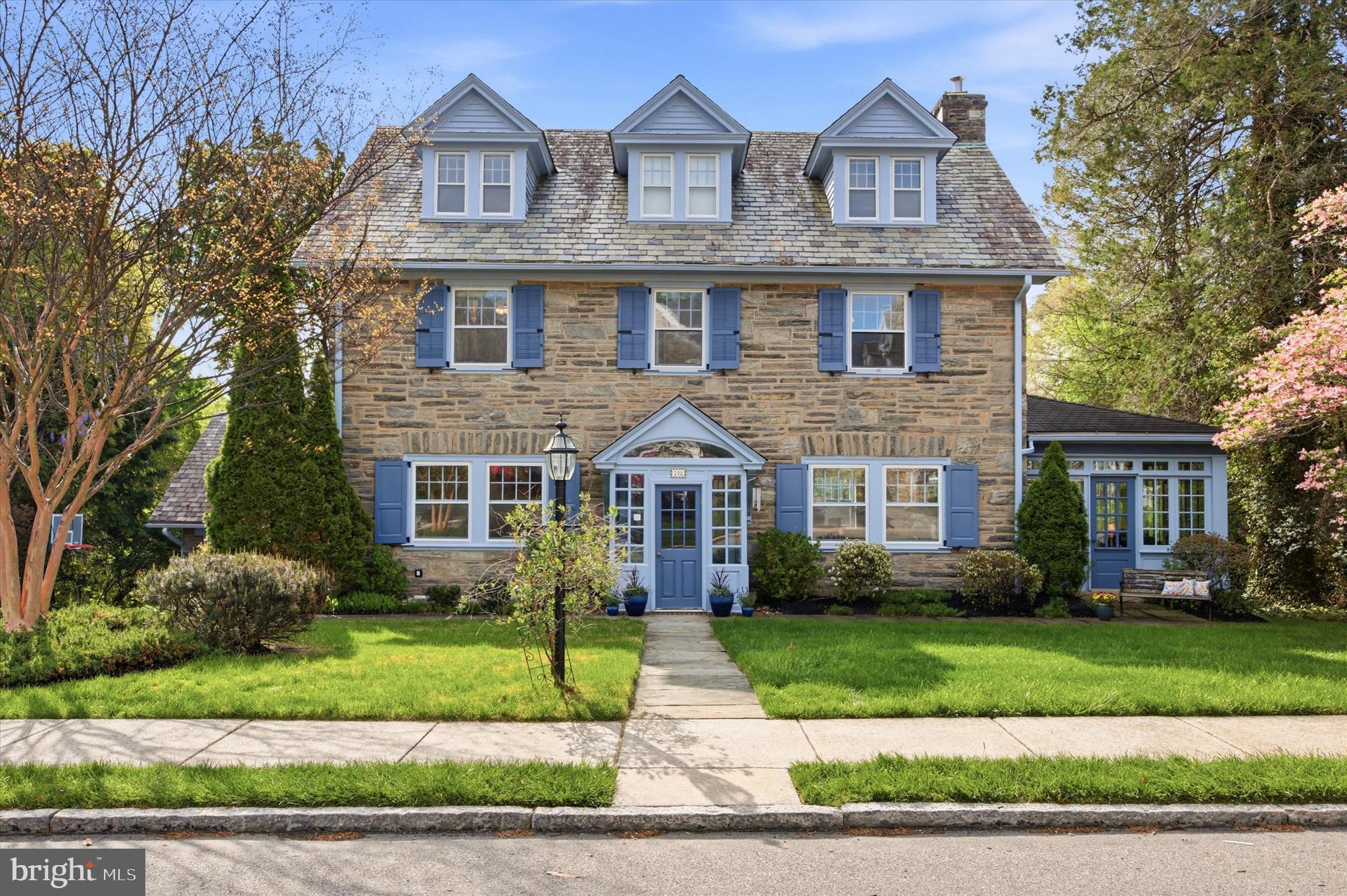 Distinguished 1923 stone Colonial gracefully set on a beautifully landscaped and private 0.32-acre parcel in the heart of Merion Station. Ideally positioned within close proximity to renowned schools, houses of worship, and local amenities, this exceptional residence offers the rare combination of a premier location, mature grounds, and over 4,300 square feet of thoughtfully designed living space. Rich in character and architectural integrity, the home showcases original stained glass windows, elegant crown moldings, chair rails, and classic French doors, all complemented by carefully maintained and updated systems. A gracious center hall entrance introduces a traditional yet highly functional layout, featuring a formal dining room and an expansive living room with a gas fireplace, both designed for refined entertaining. The adjoining sun-filled family room creates a seamless extension of the main living space, while direct access to the substantial Ipe (Brazilian walnut) wood deck allows for effortless indoor-outdoor living, overlooking the serene and well-established grounds. The kitchen is exceptionally well-appointed and designed for both everyday living and large-scale gatherings, featuring premium stainless steel appliances, including a Thermador gas cooktop, double ovens, dual dishwashers, two sinks, and a warming drawer, along with thoughtful additions such as an instant hot water system. A private study or office with custom built-in wood cabinetry provides a quiet and sophisticated workspace. The upper levels offer generous and flexible accommodations, including a primary suite with ensuite bath and ample closet space, additional bedrooms with well-proportioned layouts, and abundant storage throughout, including a cedar walk-in closet. The third floor continues to provide spacious bedrooms and a full bath, ideal for guests or extended living arrangements. The finished lower level, complete with a private exterior entrance, further enhances the home’s versatility. It includes a full bathroom, laundry, extensive storage, and a secondary kitchen, making it well-suited for extended family, guest quarters, or holiday use. Additional highlights include a slate roof, updated 200-amp electrical service, multi-zone gas heating, central air conditioning with supplemental split system, a security and fire alarm system, a new 75-gallon water heater, and an electric vehicle charger. A detached two-car garage completes the offering. Set within one of the Main Line’s most desirable neighborhoods, this exceptional property presents a rare opportunity to own a home of enduring elegance, beautifully integrated grounds, and modern comfort in an unmatched location.