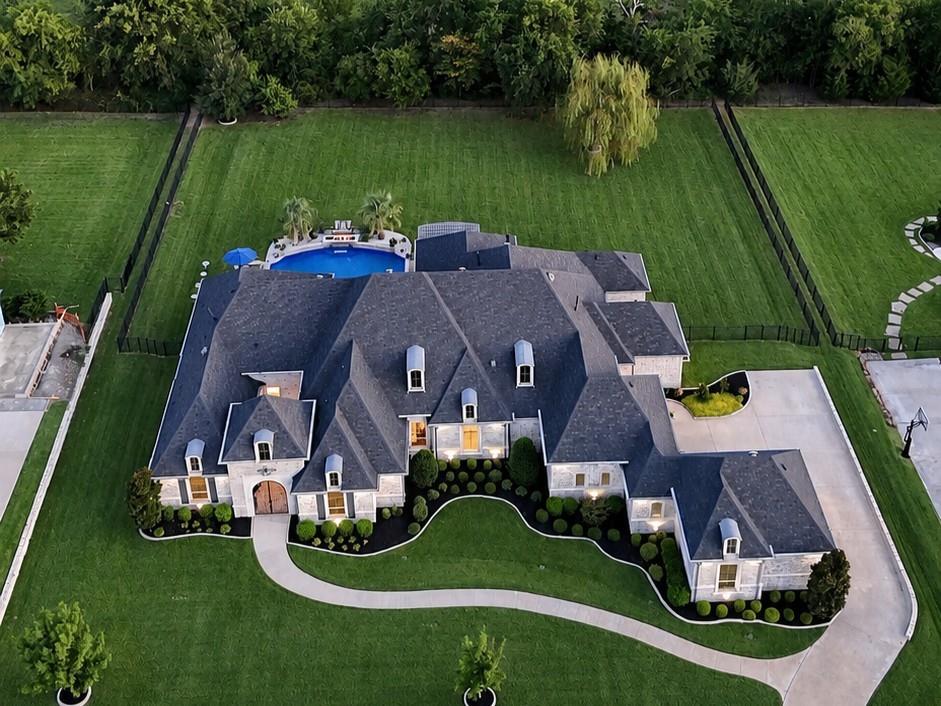 Privately situated within the gated community of Christie Farms, this custom Dave R. Williams estate blends French Chateau-inspired architecture with warm European influences across a beautifully landscaped one-acre homesite. Positioned along the exterior of the community, the property enjoys an exceptionally private, tree-lined backyard, mature landscaping, and a large, flat lawn ideal for sports, play, or future amenities.The single-story floor plan offers 5 bedrooms, 5.5 baths, with every bedroom featuring its own private ensuite. Hardwood floors extend throughout the main living areas and primary suite, while natural stone countertops are featured in the kitchen and baths. The kitchen is anchored by a 48-inch BlueStar commercial gas range with double ovens and connects seamlessly to the breakfast area and main living spaces.Beyond the bedrooms, the home includes a private office, dedicated gym, game room, formal dining, and a fully equipped media room with high-end equipment and a 160-inch screen, all conveying with the sale. Whole-home audio, oversized garages, and a discreet garage-to-pantry pass-through add everyday convenience.Nearly 1,000 square feet of covered outdoor living creates an exceptional extension of the home, complete with an outdoor kitchen and fireplace overlooking a modern pool and spa with water and fire features.Additional updates include newly painted secondary bedrooms and a 2024 Class 4 impact-resistant roof. Move-in ready and exceptionally complete, this Christie Farms estate offers privacy, architectural character, luxury amenities, and a rare combination of indoor and outdoor living in one of Prosper’s exclusive gated custom-home communities.