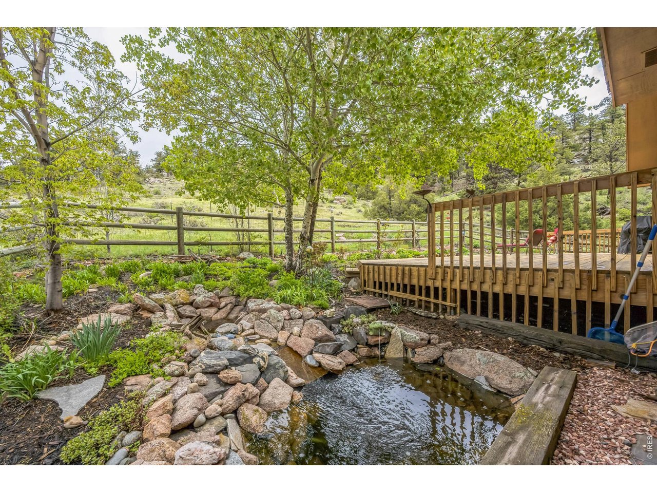Your 5.4 acre move-in ready mountain retreat, surrounded by abundant wildlife, is waiting! An open layout living and kitchen area are enhanced with exposed wooden beams, windows and doors that bring in the beautiful outdoors. You'll be glad to have the alternative heat of a whole house wood burning stove, along with large windows capturing the perfect southern exposure and sweeping mountain views. The best tasting water on the mountain is provided by a private well. A large primary bedroom overlooks the backyard's cascading waterfall and pond that attracts birds year-round. The primary bath has heated flooring, and Bose speakers can be enjoyed throughout the house and back deck. The 1200 Sq Ft redwood deck wraps around the house, offering privacy, access to a lush perennial garden, and plenty of room for outdoor living and entertaining. An expansive, newly carpeted, living space with bath opens out the basement from French doors onto a beautiful mature landscape accented with flagstone. Finally, the oversized 2 car garage provides for a work area in addition to parking. 40 minutes from Fort Collins, and 10 minutes to Red Feather