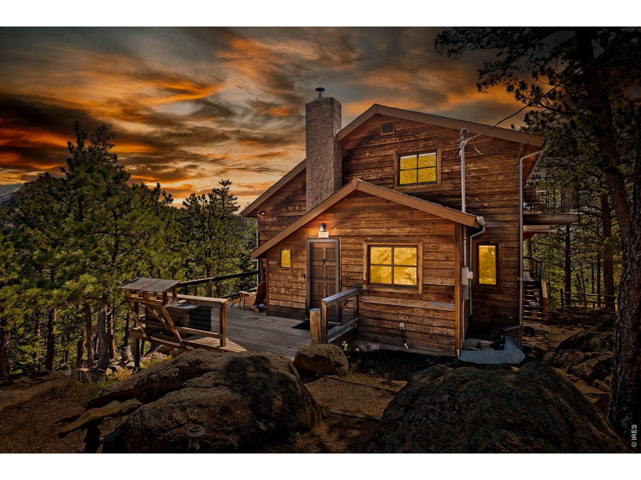 Perched among granite boulders and towering pines on nearly two private acres, 128 Elk Road is a mountain retreat unlike any other. Hand-built by a Hewlett-Packard engineer, this home reflects craftsmanship rarely found today. Every beam, window, and viewpoint was thoughtfully placed to embrace the landscape, and that spirit of creativity still resonates throughout the property. What makes this home special is how it connects you to nature. Surrounded by mature pines and granite formations, the home feels tucked into the forest-neighboring homes disappear from view and you're enveloped by trees in every direction. Large windows frame the landscape like living artwork, while birds fly past at eye level, creating the sensation of living within the canopy. Mornings begin in the sunroom, where sunlight filters through the trees and hummingbirds, nuthatches, and mountain birds gather just outside the glass-a space for slow mornings, yoga, reading, or simply sitting with coffee while the forest wakes up around you. Inside, warm wood interiors, vaulted ceilings, and expansive windows create an atmosphere both grounded and inspiring, with the fire's glow inviting cozy winter evenings. The finished loft offers a welcoming retreat for guests, and the walk-out lower level provides flexible space for hobbies or a dedicated studio-most recently a pottery studio where creativity flourished among the trees. Outside, life unfolds across nearly two acres of boulders, pines, and mountain views, with your own nature trail. Relax in a hammock among the rocks, gather around the fire pit, or host movie nights under the stars. Every corner encourages connection-to nature, to loved ones, and to yourself. The detached two-car garage and heated loft with electricity offer space for a workshop, studio, office, or guest overflow. Lovingly updated, 128 Elk Road is more than a home-a place where creativity thrives, wildlife visits daily, and the forest's rhythm shapes daily life.