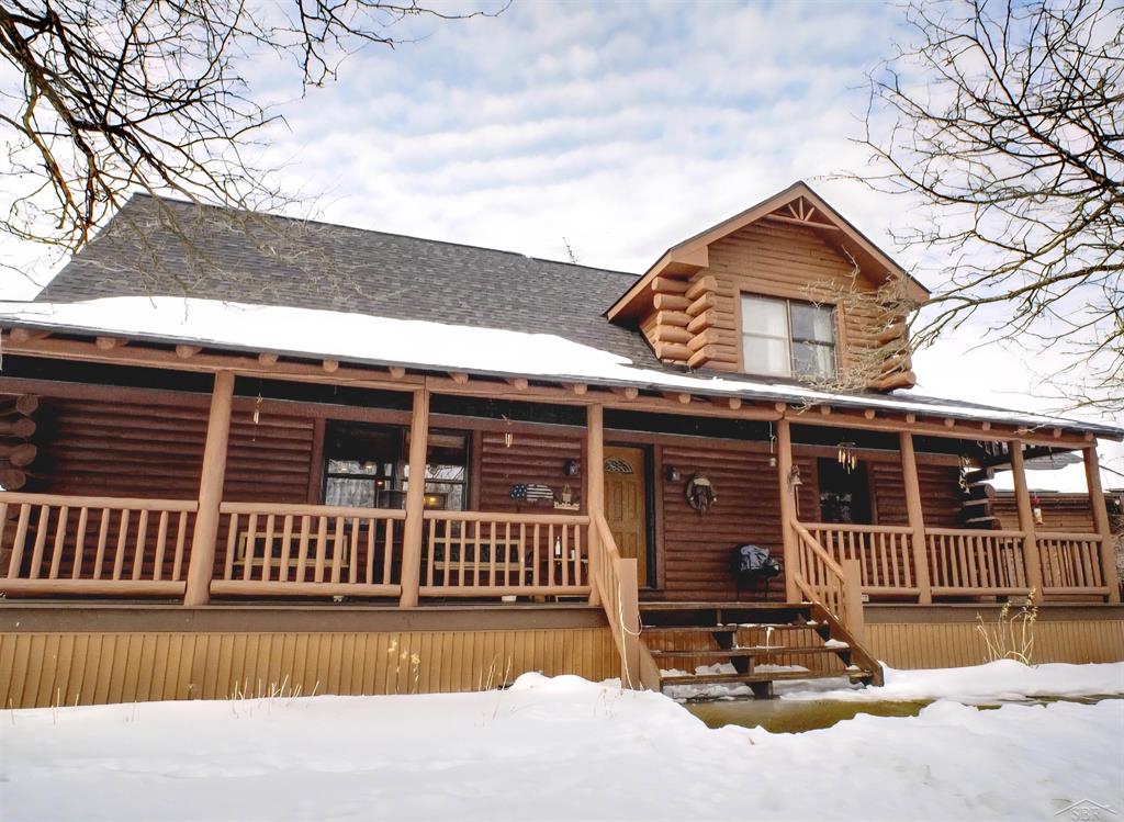 Escape to the quiet life in this stunning log home, where rustic charm meets modern comfort. Sitting on a peaceful country lot, this property provides privacy, space, and serenity. This property features cathedral ceilings, knotty pine finishes, first-floor laundry, and a wrap-around porch.   Additionally, there is an open floor plan that effortlessly blends the kitchen and living room, and a cold storage pantry for extra food storage.   The basement is divided into two sides- one side is finished and suitable for entertaining, and the other side serves perfectly as storage space. The spacious 2- car garage has electronic openers, and there is a pole barn on the property for additional outdoor storage. There is also extra loft space upstairs that would work well for an office or craft-room.  This home offers a lifestyle of comfort and peace, and it is ready for the right buyer to move right in.   Schedule your private tour today!