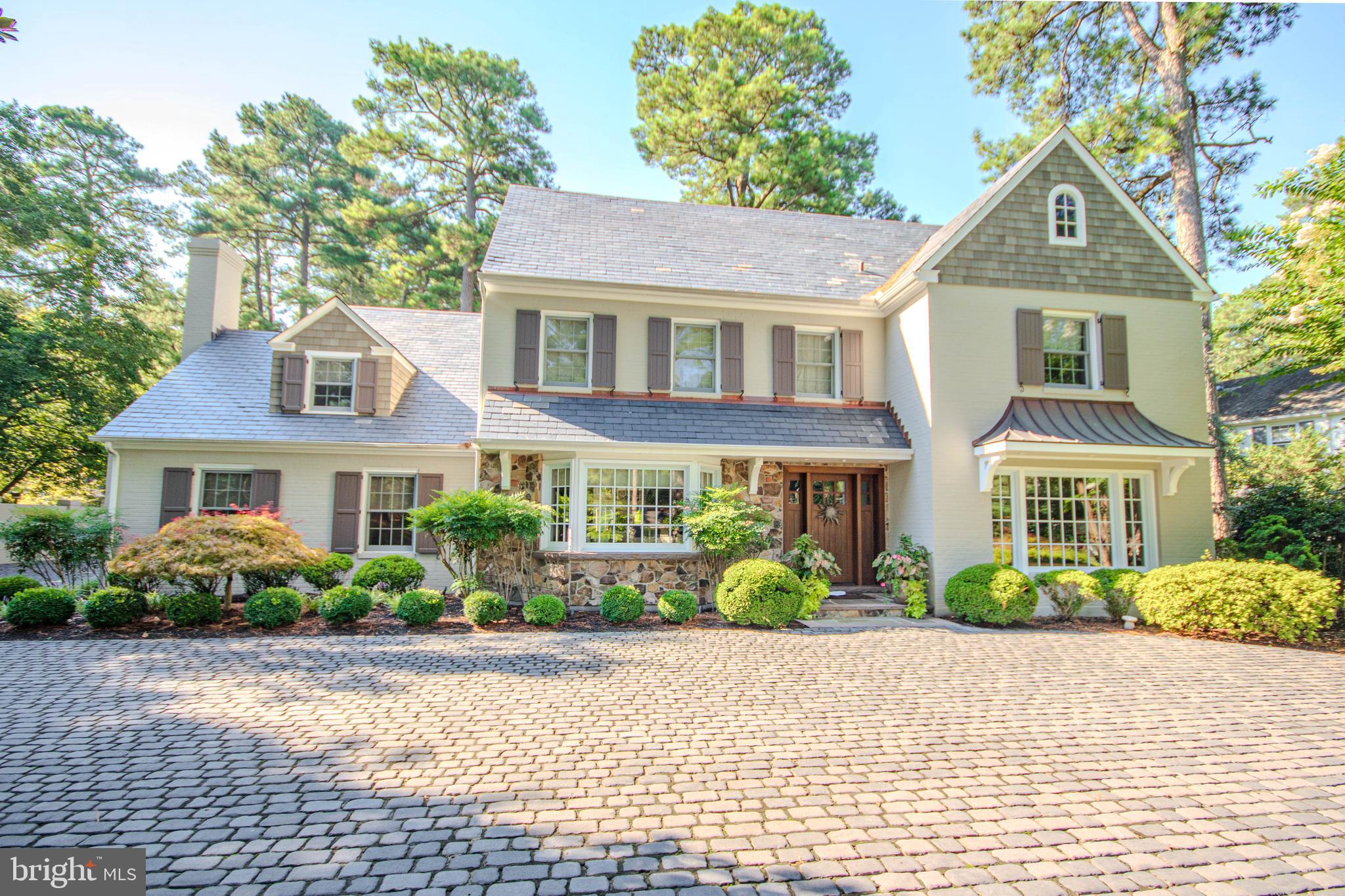 This one-of-a-kind Salisbury residence on Riverside Drive offers approximately 6,536 sq. ft., 5 bedrooms, 7.5 baths, exceptional craftsmanship, and a warm, rustic traditional style that feels both impressive and inviting. Set among stately pines on an elevated setting , the home features brick and stone, cedar-shingle accents, authentic Vermont slate roofing with copper details, custom wood doors, divided-light windows, and an expansive cobblestone drive court.Inside, rich natural materials and thoughtful architectural details create warmth and character throughout. The formal living room features a wood-burning fireplace and beautiful coffered ceiling, while the spacious dining room is accented by a grasscloth ceiling. At the heart of the home, the kitchen overlooks the pool and features leathered granite countertops, an oversized island with sink, built-in microwave, abundant cabinetry, and generous seating. Reclaimed barnwood and natural stone pillars open to the welcoming family room with a stone fireplace and built-in bookshelves. A cozy wood-paneled den features custom cabinetry, a fireplace, wood-beamed ceiling, and grasscloth details. The home's beautifully crafted interior was designed and constructed by David Lowe Construction.The spacious primary suite offers a large sitting area, beamed ceiling with recessed lighting, and private deck with hot tub. The primary bath features heated tile floors, an oversized tiled shower with dual shower heads and rain shower, and a large walk-in closet. Four additional generously sized bedrooms each offer the privacy of their own full bath.The finished lower level expands the living and entertaining space with heated floors, a full bar with leathered countertops, full bath, and two bonus rooms. Additional features include a custom-finished laundry room, finished attic, and large detached finished garage connected to the home by a covered colonnade. A heated and cooled bonus room above the garage provides even more flexible space.Outdoor living is a highlight of the property, with a heated in-ground pool, expansive natural bluestone terrace, and fully appointed pool house cabana surrounded by mature trees and professionally designed, lighted, and irrigated landscaping by Bryan Lecompte and Yard Design. The result is a private and welcoming backyard equally suited for entertaining, family gatherings, or simply relaxing at home.Beautifully crafted without feeling formal and spacious without feeling overwhelming, this remarkable Riverside Drive property offers a rare combination of warmth, privacy, recreation, and convenience. Located in the heart of Salisbury, it offers the added benefit of city services with only county taxes—a truly special home designed for comfortable everyday living, entertaining, and making memories.OPTIONAL:  0.62-acre lot at 1105 Woodland Road, currently utilized as a private mini sports complex. This additional parcel provides an incredible recreational component with space for sports, outdoor activities, gatherings, and future possibilities.