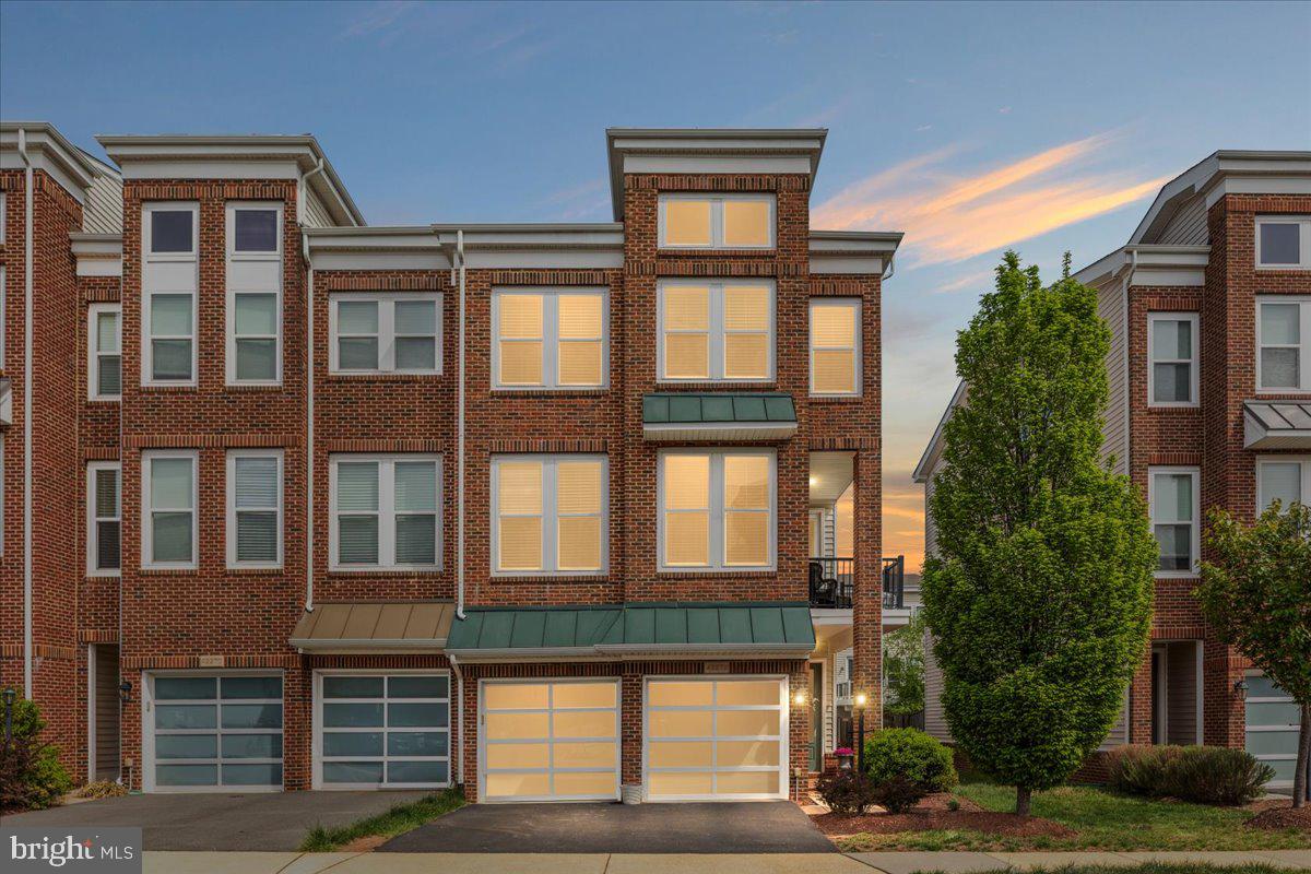 The very Best of Brambleton! Expansive (3263 sq ft!) end-unit garage townhome with a unique contemporary floorplan designed for modern lifestyles, including ENTRY LEVEL main living areas - no more walking up stairs right when you get home! The main level boasts 5" wide plank engineered wood floors and an open concept designed to enhance connections or make entertaining a breeze. Spacious family room with gas fireplace flows into the adjacent dining area and the gorgeous gourmet kitchen - featuring oversized center island, sleek white cabinetry, granite counters, and stainless steel appliances (check out that gas cooktop with ceiling mounted range hood and recently replaced dishwasher too!). Glass door leads out to a picturesque fully fenced rear yard with an updated paver patio made for flipping burgers and summer gatherings.  Upstairs an idyllic primary retreat awaits you, with sitting room, tray ceiling, dual walk-in closets, and luxury bath with separate vanities, soaking tub and stall shower. Upper Level One is also home to a convenient laundry room featuring recently replaced washer and dryer, sunny balcony (your morning coffee is calling!) and a fantastic flex space - perfect for a home office or den. Upper Level Two features a second bedroom suite the family will fight over, 2 additional bedrooms, full hall bathroom, and a large loft - you could purpose this space as a play or homework room, teen hangout, gaming area, or gym! Brambleton is a favorite Loudoun neighborhood for good reason: top tier amenities (pools, parks, playgrounds, sports courts, 20 miles of trails), community events throughout the year, enviable proximity to shopping / dining / movies / golf courses / library, and a monthly HOA fee that includes trash, cable, internet, and limited lawn care!! Plus a desirable location with easy access to Dulles Greenway, LoCo Pkwy, 28, 50 and the Ashburn Metro Station. This one has it all, and you can see for yourself soon - showing start Thursday May 14th!