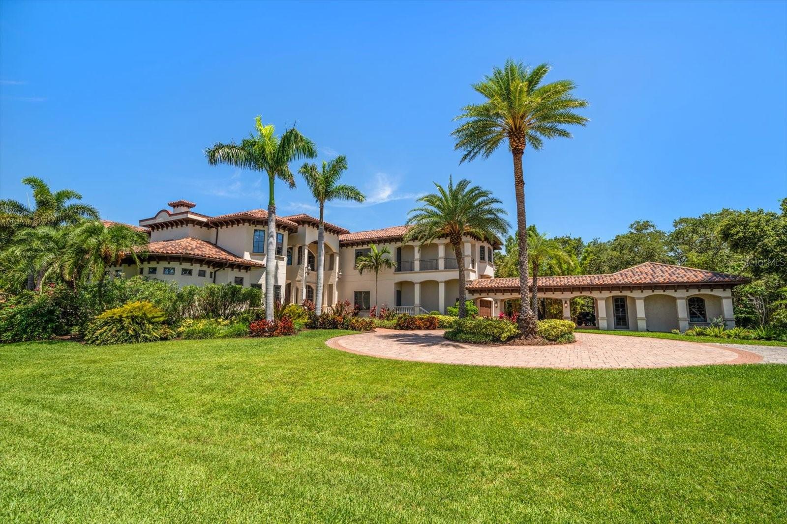 An estate where two elite worlds collide- WATERFRONT luxury & EQUESTRIAN prestige. Tucked away behind a canopy of majestic oaks, a winding Tennessee fieldstone driveway leads you to a Mediterranean-inspired masterpiece that redefines elegance and luxury. Crafted by renowned Brandon Construction, this private estate is a true tropical paradise, created for those with the most discerning taste. Custom double entry doors open to an awe-inspiring interior—where sophistication and thoughtful design meet. The private office offers quiet productivity, while the breathtaking living and dining room commands attention with soaring floor-to-ceiling windows that perfectly frame the resort-style pool and lush outdoor living areas. The chef’s kitchen is the heart of the home, featuring granite countertops, a center island with prep sink, breakfast bar, pot filler, custom built-in Miele fridge & freezer, gas cooktop, and a walk-in pantry—all open to a warm and spacious family room with beamed coffered ceilings, a cozy fireplace, and sliders to the outdoor oasis. Every detail has been considered, from the pool bath, mudroom, and laundry room to the theater room with stage and stadium seating—ideal for movie nights or performances. The primary suite is a serene retreat, flooded with natural light and accented by rich wood beams, a jaw-dropping custom walk-in closet with center island, and a spa-like bath with jetted tub, double walk-in shower with triple heads, dual vanities, a dressing table, and a hidden passage to the home office. Additional bedrooms and bathrooms are designed to pamper family and guests alike. Step outside and you’re transported to your own luxury resort—complete with a two-level heated pool and spa, outdoor kitchen, fireplace, and multiple entertaining areas. For boating enthusiasts, a TREX dock with a 10,000 lb lift offers direct access to the Intracoastal, while west-facing views provide spectacular sunsets that melt into the Gulf. But the crown jewel of this estate may be its custom-built barn—featuring rubber paver flooring, stalls with custom cushion mats, a tack room with custom saddle racks, feed room, covered and lit riding arena for nighttime rides, and a loft with full kitchen and bath, perfect for an on-site trainer or in-law suite. Spring-fed streams weave through the grounds, adding a touch of magic to this must-see property. Overlooking the Narrows and nestled in nature yet minutes from shopping, dining, and the beach—this is more than a home; it’s a once-in-a-lifetime opportunity to live your dream.