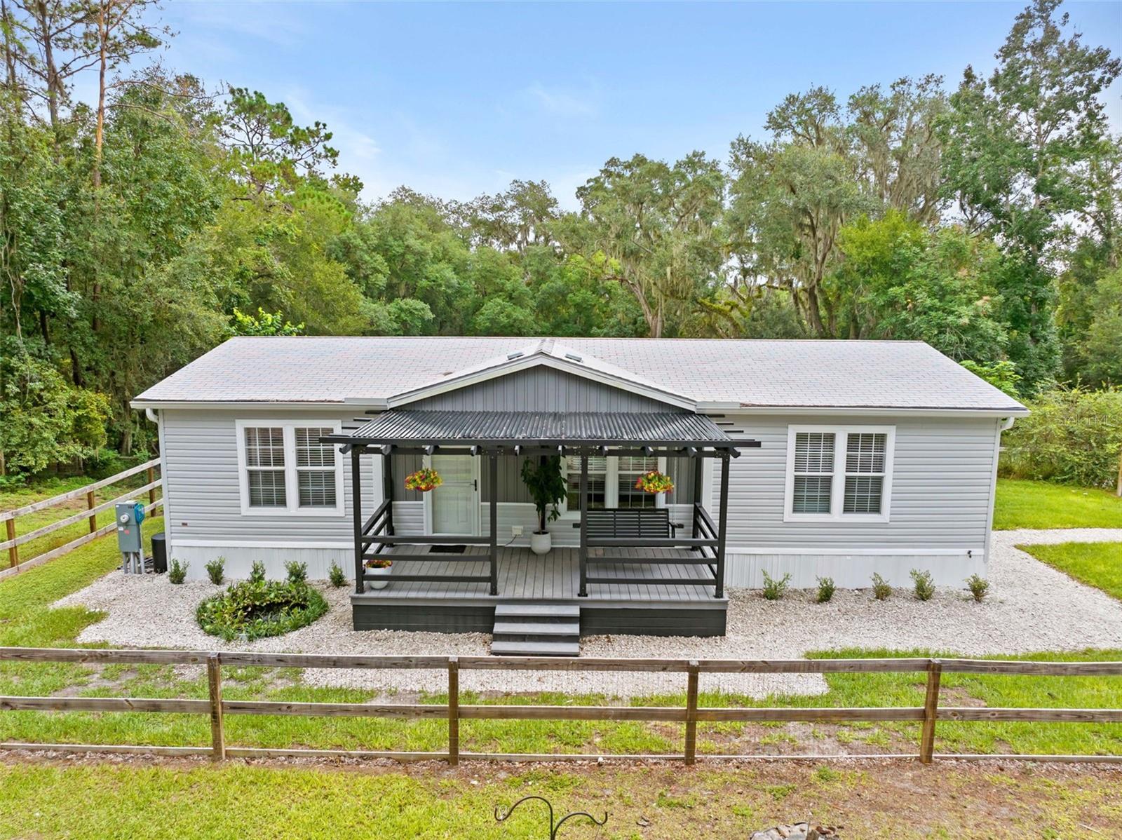 Tucked among the picturesque rolling hills of Hernando County, 1164 Katie Wood Trail offers something increasingly difficult to find in Central Florida: 8 private, fully fenced acres, exceptional elevation, beautiful pastoral views & no neighbors in sight, all paired with a nearly new home & thoughtfully developed agricultural infrastructure. Situated at the end of a quiet dead-end road & approximately 180 ft above sea level, the property welcomes you through a private gated entrance into a setting that feels worlds away. Green hay fields, mature trees, established landscaping and abundant wildlife surround the homesite, creating the peaceful atmosphere of a secluded country retreat. Built in 2024 by Jacobsen Homes & maintained in pristine condition, the 3 bedroom, 2 bath residence offers a bright, inviting interior designed for comfortable everyday living. An open-concept floor plan connects the spacious living area with a beautifully finished neutral kitchen featuring stainless steel appliances, while the split-bedroom design provides privacy for family & guests. The primary suite overlooks the surrounding acreage & features a walk-in closet & spacious ensuite bath with dual vanities & a large shower. 2 additional bedrooms and a full guest bath are positioned on the opposite side of the home, making the layout equally well suited for family, overnight guests or a dedicated home office. But what truly distinguishes this property lies beyond the home. Step onto the expansive rear porch & take in sweeping views across the property's terraced natural Florida landscape. Hidden beneath the porch & built directly into the hillside is an approximately 1,250-square-foot agricultural-zoned bunker; an extraordinarily rare feature offering tremendous versatility. Its potential uses range from agricultural purposes such as raising poultry or small animals & cottage-food production to a private office, storage, hobby space or storm shelter. A separate 20x20 fully enclosed garage/workshop with 2 overhead roll-up doors provides additional space for equipment, tools, ATVs, tractors & recreational toys. For those dreaming of a working homestead or hobby farm, the infrastructure is already here. Livestock fencing, shelters, gates & watering systems have been thoughtfully established throughout the property, eliminating much of the expense & work normally required to transform raw acreage into a functional farm. Even the poultry have their own address! Welcome to the Sunny Side Up Saloon, a custom predator-resistant luxury chicken coop featuring protected roosting areas & multiple elevated brooder enclosures ideal for chicks, quail, rabbits & other small animals. It's a charming detail, but also another example of how carefully this property has been developed for practical country living. Spend your mornings enjoying coffee from the front porch as the sun comes up over the hay fields. Watch deer and wildlife move through the property. Bring your animals, garden, homestead, work from home or simply enjoy the increasingly rare luxury of having 8 acres of some of Florida's beautiful rolling countryside entirely to yourself. This isn't simply a home with acreage. It's a private, established homestead where the land, improvements & infrastructure have already been brought together for you. Properties with this combination of privacy, improvements & character rarely come to market. Schedule your private showing and experience 1164 Katie Wood Trl for yourself.