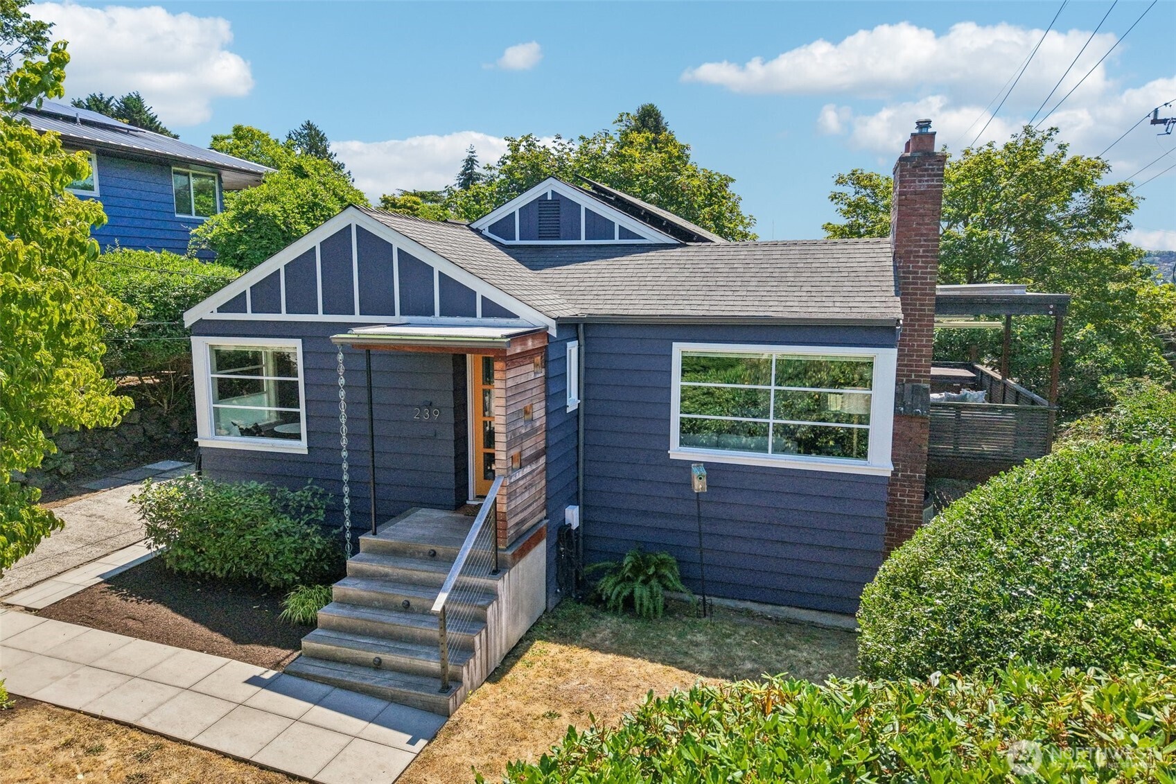 This captivating Cape Cod-style home in the heart of Phinney Ridge is the perfect blend of timeless character and modern comfort. A unique street to street corner lot with stunning sunset views. Warm hardwood floors and light-filled living spaces create an unforgettable first impression. A Viking 6 burner gas cook stove, high end appliances, barn door style pantry and unique concrete counters anchor this chef's kitchen which opens seamlessly to living/dining areas. Corner windows flood the home with abundant light and views of the Olympic Mountain range. A stunning wall of glass doors, Nana Wall style bi-fold doors, open fully to a heated covered deck with a hot tub, an ideal extension of your living space for all season's comfort and entertaining. Two bedrooms on the main, one with glass doors to the deck. The lower-level primary suite offers a peaceful retreat with a spacious walk-in closet, bath and seating. Enjoy a spacious media room with large viewing screen and built in projector! This is where your friends will want to watch all the games. Comfort and sustainability come together with heat pump air conditioning, solar panels, and an EV electric car charger. Full of personality, upgrades, and exceptional indoor-outdoor living, you'll fall in love with this home.