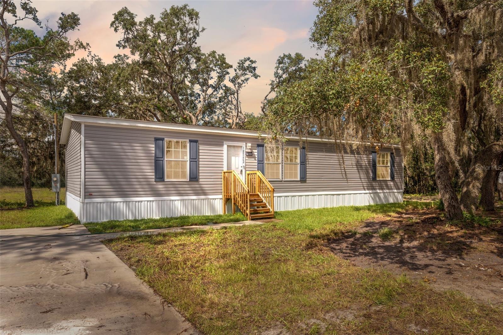Brand New 3 Bed / 2 Bath Home on 1.8 Serene Acres (No Lot Rent)– Built by Champion. Welcome to your slice of Florida paradise! This beautifully crafted, brand new 3-bedroom, 2-bath home by Champion sits gracefully on 1.8 acres of natural Florida landscape, surrounded by mature oak trees that offer both shade and privacy. Enjoy peaceful mornings and quiet evenings from the expansive, newly built wrap-around front porch, where you can take in tranquil views of your oversized, freshly installed driveway—perfect for storing vehicles, boats, or toys. The backyard offers serene seclusion with distant rear neighbors, making it an ideal space for relaxation or entertaining. The home also features a brand new septic system installed with the build, ensuring everything is move-in ready and low maintenance. Situated on a paved road with easy access to major highways, this property offers the rare combination of rural charm and modern convenience. Whether you’re looking for a peaceful homestead or a weekend retreat, this is your chance to own a true piece of Florida living. Don’t miss this opportunity to claim your own private haven—schedule your showing today!