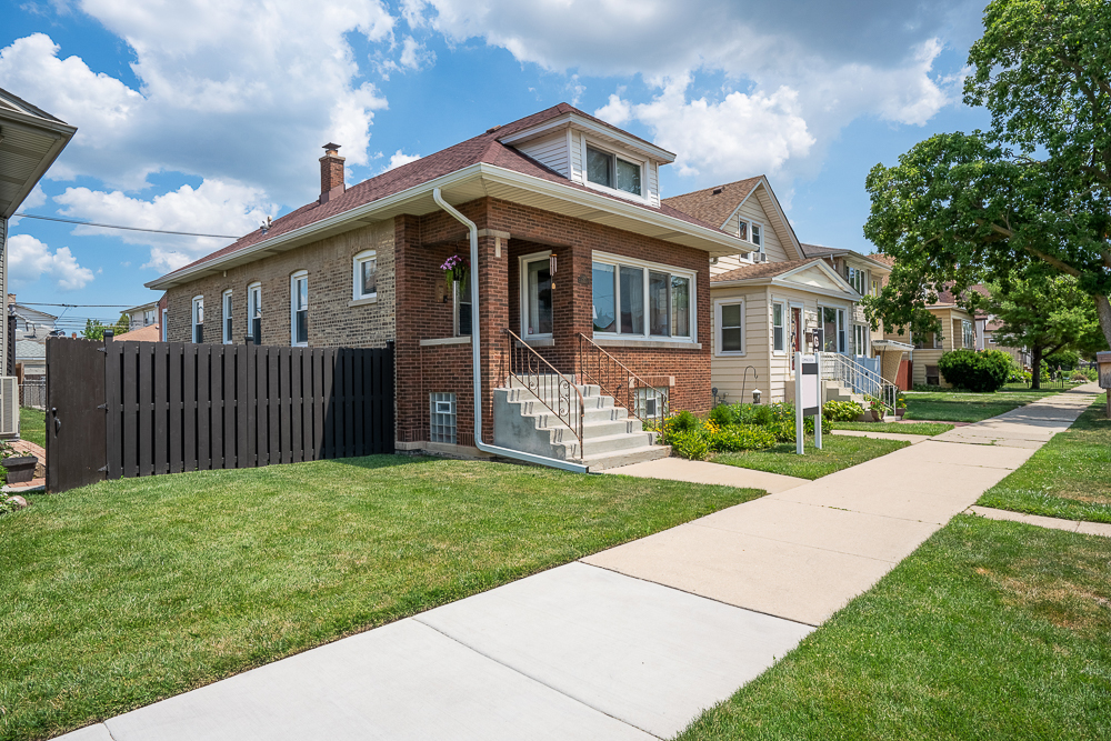 This meticulously cared-for bungalow in Chicago's desirable Portage Park neighborhood blends vintage charm with modern comfort and versatile living spaces. A welcoming vintage foyer opens to a sun-drenched living room and formal dining room filled with natural light, both featuring original oak hardwood floors, while the kitchen showcases maple flooring. The updated kitchen (2021) features stylish cabinetry, a tile backsplash, and a walk-in pantry-perfect for everyday living or entertaining. The main floor includes a spacious primary bedroom and a second bedroom that opens to a bright, heated sunroom-an ideal spot for morning coffee, a cozy reading nook, a plant-filled retreat, or a cheerful home office. Spend summer evenings relaxing in the pool or unwinding with drinks on the deck, enhanced by outdoor Bose speakers and a two-car garage featuring a convenient "party door." The finished basement offers two bedrooms, new flooring throughout (2023), a summer kitchen, and its own private entry-easily used as a rental or Airbnb for extra income or multi-generational living. New 6-inch gutters were added in 2023, and the full attic remains blank, ready for your vision. Situated just minutes from the iconic 36-acre Portage Park-offering a pool, tennis courts, walking trails, and community events-and close to the bustling Six Corners district with its eclectic mix of shopping, dining, and neighborhood favorites, this home offers timeless character, thoughtful updates, and access to one of the Northwest Side's most vibrant communities. Excellent public transit options nearby include the CTA Blue Line, Metra, and multiple bus routes.