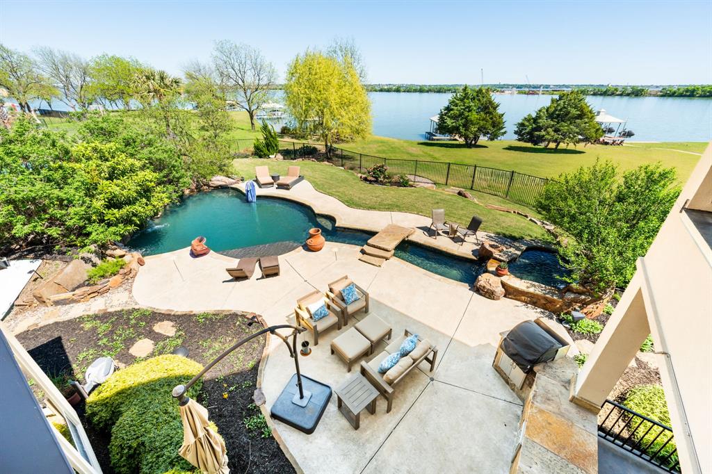 East facing waterfront homes of this caliber are seldom available, especially within an intimate gated community of just eight residences. At 2210 Stone Hollow Drive, luxury is a lifestyle. The home is framed by thoughtfully curated grounds designed by a board member of Keep Rowlett Beautiful. The landscaping blends beauty and purpose, with low-maintenance, pollinator friendly plantings creating a serene setting. Inside, the home unfolds with effortless elegance. A two story foyer welcomes you into light filled living spaces where walls of windows frame the pool and lake beyond. The expansive living room with stone fireplace flows seamlessly into a chef’s kitchen designed for both daily living and elevated entertaining, featuring an Italian oven and cooktop, built-in refrigeration, and an oversized walk-in pantry with room for a refrigerator. The master suite is a private sanctuary offering a sitting area, tranquil water views, and a beautifully appointed bath and custom walk-in closet. Upstairs, spacious en-suite bedrooms including a second master suite offer comfort and flexibility, with a second laundry room and private balcony access, ideal for guests or multi-generational living. Outdoors, the experience becomes extraordinary. A covered patio with fireplace, resort style saltwater pool with swim jets and spa, and outdoor built in grill create an unparalleled setting for entertaining. A stone pathway leads to a terraced lakeside retreat perfect for evenings by the fire pit or dining under the stars. The private dock is fully equipped with a boat lift and two jet ski lifts offering effortless access to the water. Every detail has been considered, including a whole house generator, water purification system, mosquito misting system, spray foam insulation, and an in-ground storm shelter. Set in Rockwall County and the highly regarded Rockwall ISD, this is a rare opportunity to experience elevated waterfront living in one of the area’s most exclusive settings.