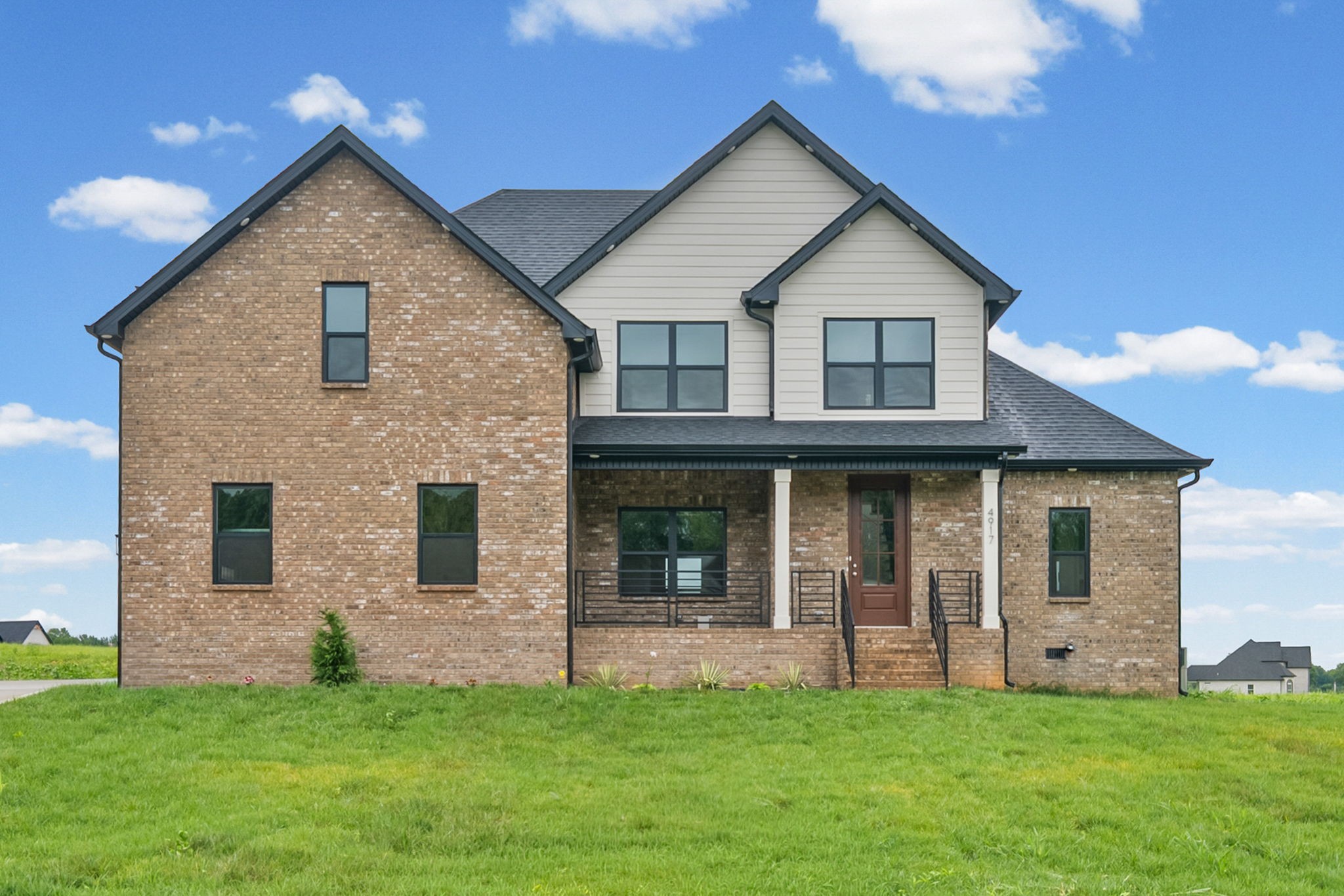 New construction brick home with covered porch, landscaping, and spacious lawn in Clarksville TN