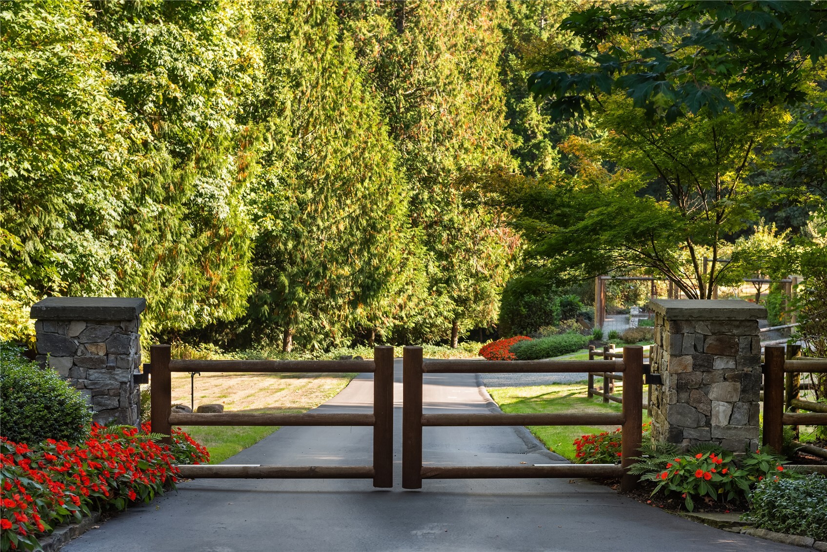 Wood entry gate with stone pillars and tree-lined driveway