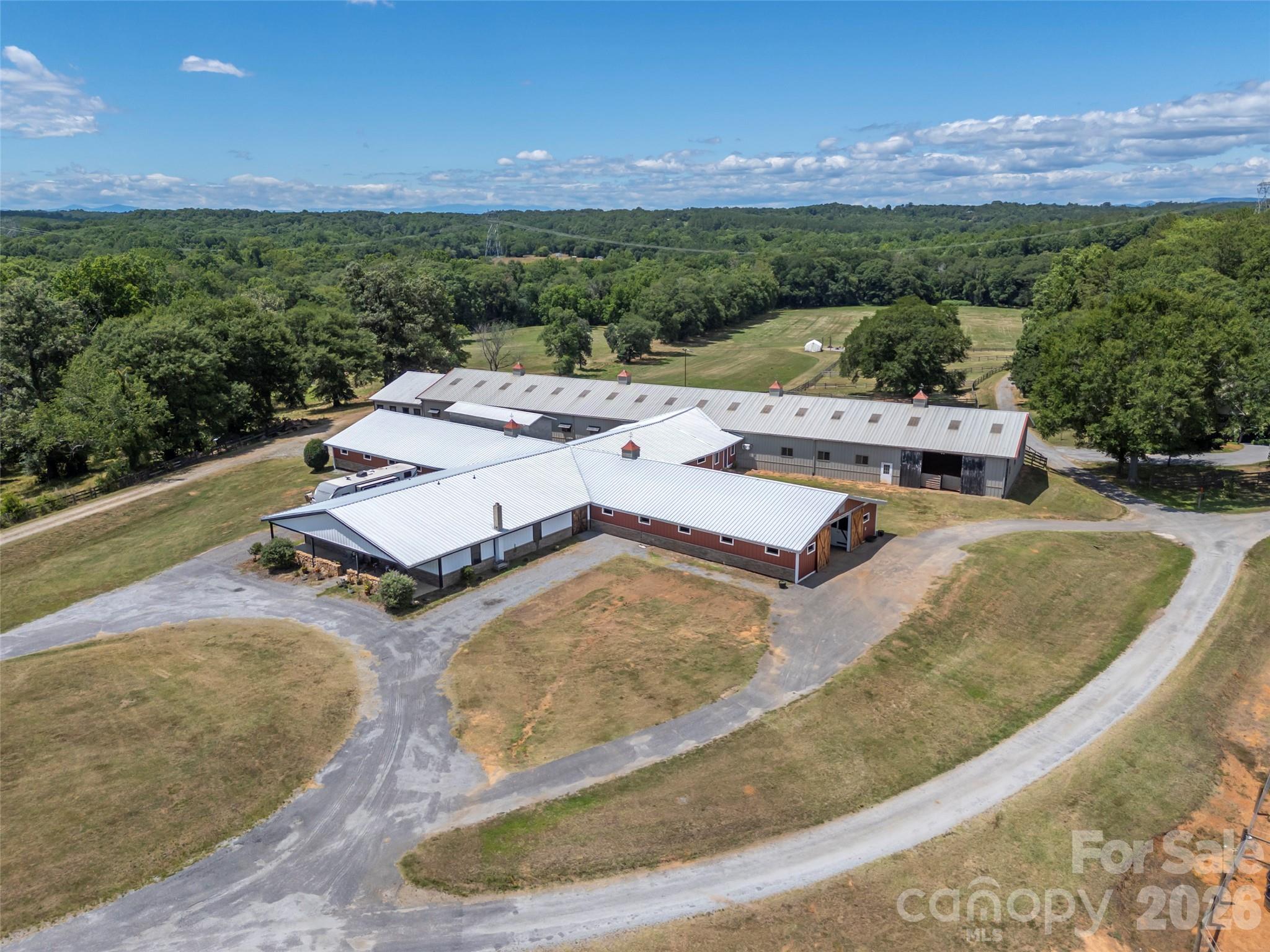 Set along the banks of the Broad River, this extraordinary 84.49-acre equestrian estate offers a rare opportunity to own one of the Southeast's premier horse farms. More than just a beautiful property, this is a fully operational equestrian facility where luxury country living and professional-grade infrastructure come together in an unforgettable setting. As you make your way down the private drive, rolling pastures, productive hay fields, and sweeping river views immediately set the tone. Nearly 85 acres of usable land provide endless possibilities, whether you're operating a premier training and boarding facility, expanding a breeding program, or creating the private family farm you've always envisioned. At the heart of the property is an impressive 29-stall barn designed for serious horsemen. Thoughtfully updated and exceptionally maintained, it features both indoor and outdoor riding arenas, multiple tack rooms, a heated and cooled wash room, a comfortable viewing room, round pen, trailer storage, and the infrastructure to support a thriving equestrian operation. A private two-bedroom apartment within the barn offers the perfect space for a trainer, farm manager, staff, or extended family to stay close to the horses. The residence overlooks the farm's picturesque landscape, with panoramic views stretching across lush pastures and open fields. After a day at the barn, unwind by the in-ground saltwater pool, enjoy a game on the private basketball court, or simply take in the peaceful beauty that surrounds you. Less than 25 minutes from Tryon International Equestrian Center and centrally located to Asheville, Charlotte, and Greenville-Spartanburg airports, the farm offers exceptional functionality. Approximately 28 acres are dedicated to productive hay fields, creating income potential, while nearly three-quarters of a mile of Broad River frontage adds both beauty and recreation to this remarkable property. Whether you're searching for a world-class equestrian facility, a luxury private family compound, or an investment in one of North Carolina's most desirable horse properties, this exceptional farm delivers a rare combination of scale, beauty, and capability that is seldom found and even more rarely offered. NO DRIVE BYS! PLEASE DO NOT DRIVE DOWN JOANDA FARM ROAD. Call for an appointment.