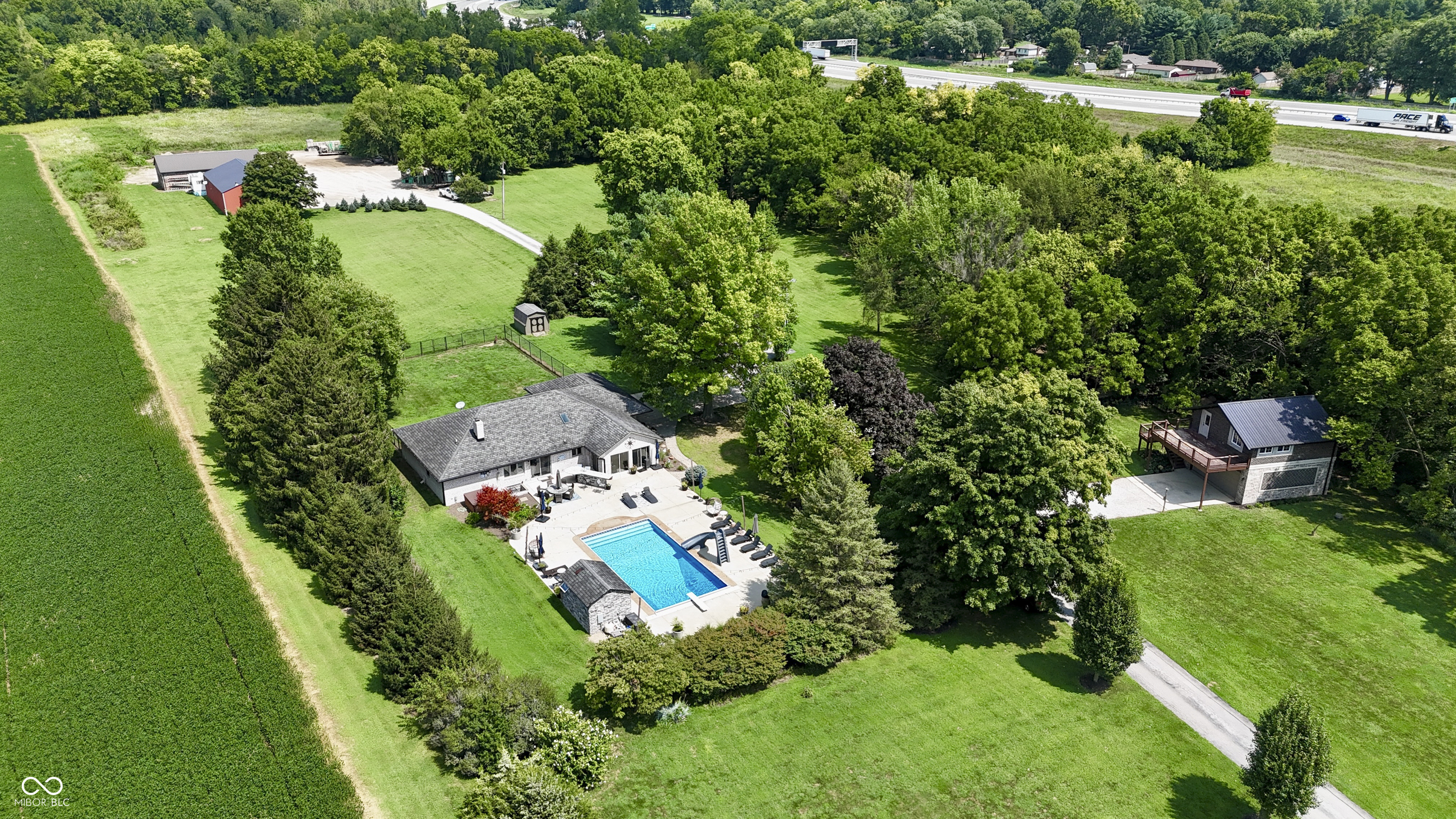 This rare 13 Acre Perry Township property blends residential luxury with functional versatility. The main home features 5 bedrooms and 3.5 bathrooms with many updates throughout. The large and inviting kitchen boasts stainless steel appliances and a large center island with granite countertops and ample storage. In this open concept design, the kitchen space opens up to both the breakfast area and cozy living room with its wood fireplace while also flowing out to the peaceful glassed-in porch. This home is perfect for family fun and entertaining with the finished basement and high-end swimming pool, pool house and hot tub. The main home is complemented by an additional dwelling unit with approx 1,000 sq ft of finished living space including 1 bed, 1 bath, kitchen and living area. Multiple barns provide generous storage for vehicles, equipment, or materials, as well as several dedicated office spaces. High-end masonry throughout the structures reflects timeless craftsmanship, quality and durability. From a tree lined drive to pasture areas and backyards for family fun to wooded areas surrounding the property with wildlife making frequent visits - this property creates an oasis in the midst of local convenience. Come and make this highly desirable property your own!