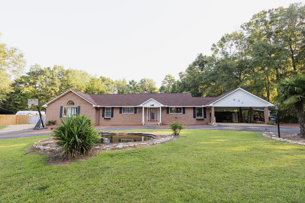 Tucked into an established in-town neighborhood, 1709 Wimbledon Drive offers the rare combination of generous living spaces, a private 1.798-acre setting, and a backyard designed for enjoying the South Georgia lifestyle. With 3,199 square feet, this freshly painted brick ranch has room to spread out while still feeling comfortable and inviting.  Inside, a private entry foyer creates a welcoming transition into the home. The large family room is filled with natural light from picture windows overlooking the backyard and features a cathedral beamed ceiling that adds character and a wonderful sense of scale. The adjoining dining area is partially open to the family room, with open shelving providing a subtle division between the two spaces. Enjoy a cozy seating area by the fireplace which is convenient for reading, working or visiting with friends and family.  The kitchen has a relaxed feel with a granite countertop center island and built-in banquette for casual meals and morning coffee, along with convenient access from the double carport. Laundry room is tucked away by back door and has additional storage for pantry items.  Generous proportions continue in the primary suite, where a high ceiling and plenty of space allow for a separate sitting area. A door opens directly to the screened porch, while the bath includes a double-sink vanity, tiled shower, and walk-in closet. Two additional bedrooms share a hall bath with a double vanity and tiled shower. An oversized bonus room with a vaulted, beamed ceiling provides even more flexibility for a media room, playroom, home office, hobbies, or additional gathering space.  Outdoor living is an important part of this property. The screened porch opens to a large deck overlooking the pool and pool gazebo, creating an easy flow from indoor living to afternoons by the water and casual entertaining with family and friends. A small pond and fountain in the front circle driveway add another welcoming touch to the setting.  Located near the hospital and medical facilities, schools, shopping, and the country club, the home feels private while remaining in the heart of an established Thomasville neighborhood. With its large rooms, flexible living spaces, pool, and convenient location, 1709 Wimbledon Drive is ready for its next owners to make it their own.