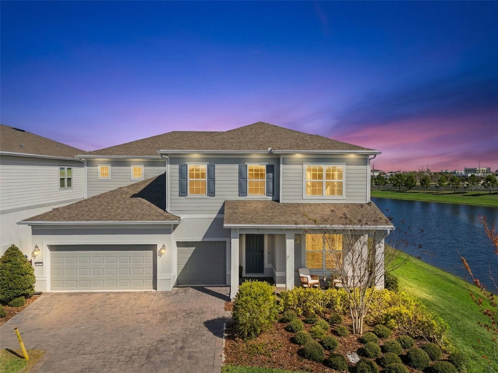 Some homes have a water view. This one has water on two sides, wrapping around a rare corner homesite (ONE OF 11 in the community) where water views follow you from room to room. Built in 2022 on .20 acres with over $400,000 in lot premium, structural, and design options, every detail of this 3,826-square-foot home was considered, and it shows. That connection to the water carries straight through to the outdoor living experience. Pocket sliding glass doors open the living room to a 43-foot lanai with automated screens, where surround sound sets the mood and the pool sits just beyond. The salt chlorinated, gas-heated pool is finished with a pebble interior, flagstone paver surround, and a heated spa with therapy jets, and a pool bath with frameless glass shower and pre-plumbing for an outdoor kitchen means this backyard is ready for anything. Step inside and the first floor makes an immediate impression with 10-foot 8-inch ceilings, 8-foot doors, and engineered hardwood stretching from wall to wall. The kitchen anchors the space with Calacatta quartz countertops, a gas cooktop with a vented hood, built-in microwave and oven, soft-close cabinetry with decorative end panels, a single-basin granite sink, and a large true walk-in pantry. A private office with double French doors, a built-in drop zone off the garage, and generous storage throughout round out a floor plan that is as thoughtfully designed as it is livable. Upstairs, 10-foot ceilings continue the sense of openness, and the primary suite is where this home earns its place. Water views stretch across the bedroom, follow you into the walk-in closet, and stay with you in the spa bath, where dual sinks and a walk-in shower with a dedicated seating area make the morning routine feel like anything but. Three additional bedrooms each have their own walk-in closets, a full ensuite with private bath rounds out the upper level, and a spacious loft ties it all together. The staircase, finished with engineered hardwood treads and open spindles that wrap the loft railing, blends the upstairs and downstairs living spaces with an open feel. The sellers made deliberate investments in how this home lives beyond what the eye can see. Foam-filled block construction, a Lennox PureAir system with MERV 16 filtration and UV light, and a whole-home water softener and filtration system sit alongside a tankless gas water heater and smart home features including a wireless access point system, smart garage opener, smart thermostat, and smart door lock. Outside, a paver driveway, gutters, full fencing, EV charging in the three-car garage, and soffit outlets for exterior lighting complete a home where nothing was left as an afterthought. The HOA includes gated access through two entrances, one reserved exclusively for residents, 1-gigabit high speed internet, and landscaping maintenance, so the weekend is yours to enjoy. Isles of Lake Nona offers a resort-style pool and splash pad, fitness center, pickleball and tennis courts, an event room, on-site management, and scenic ponds throughout the community, all just outside your door. This homesite was made for someone who wants to live well every day. The water is always there, the sunsets are yours, and there is simply nothing else like it in the community!