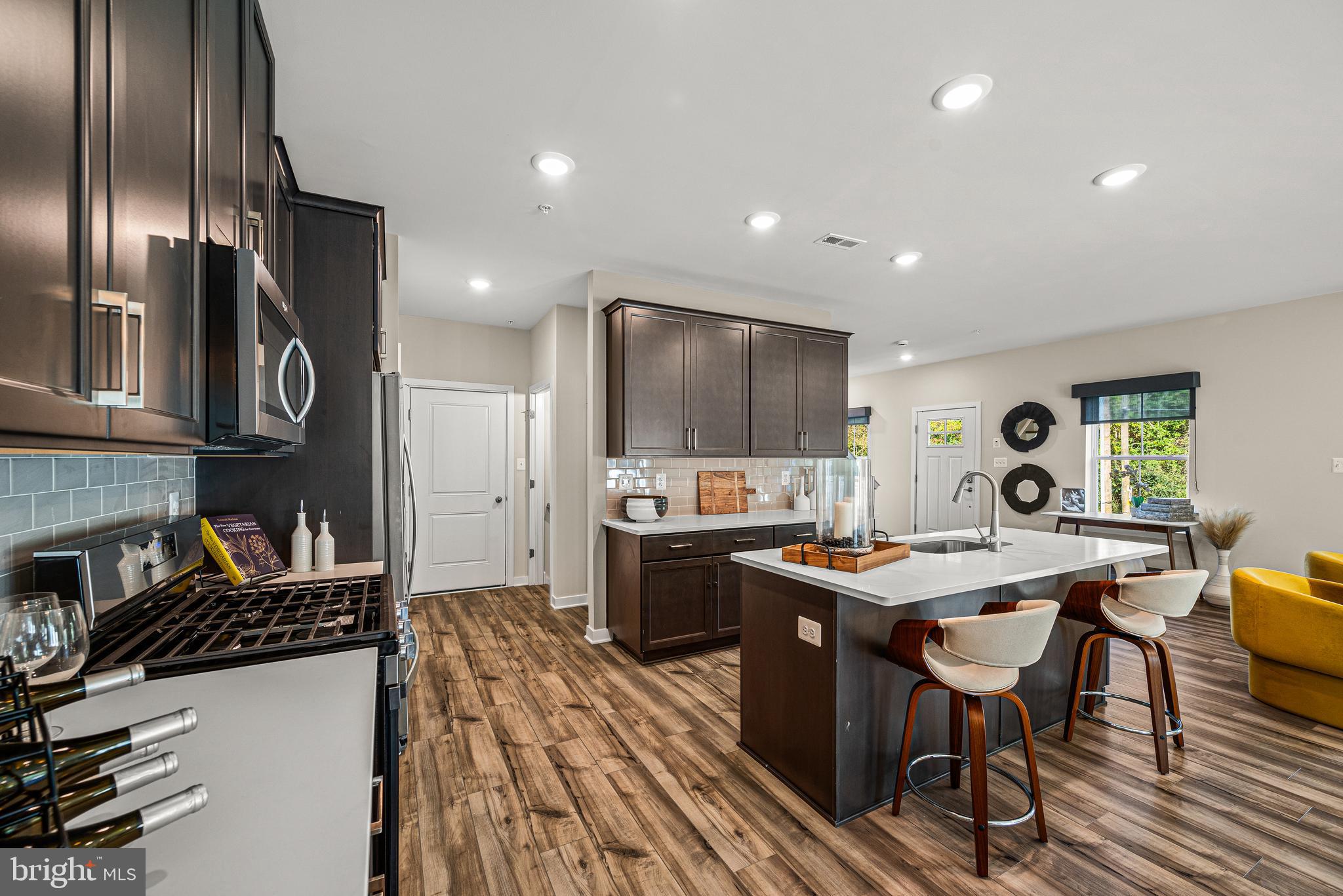 Built as Clover Mill's decorated model and never lived in, this end-of-row townhome carries the kind of details most homeowners spend years adding: custom architectural trim, designer wallpaper accents, statement lighting, and custom window treatments already in place. The kitchen anchors the main level with quartz counters and an oversized island, opening to a living area with wide plank flooring that flows to a low-maintenance deck. The primary suite offers a quiet upstairs retreat, and the finished lower level with powder room flexes as a gym, lounge, or second living space. Generous closets and storage throughout. Two-car garage plus driveway parking. The HOA covers walking trails, common areas, snow removal, trash, and recycling. Within the Downingtown East School District and STEM Academy boundary. Home does not include the furniture.
