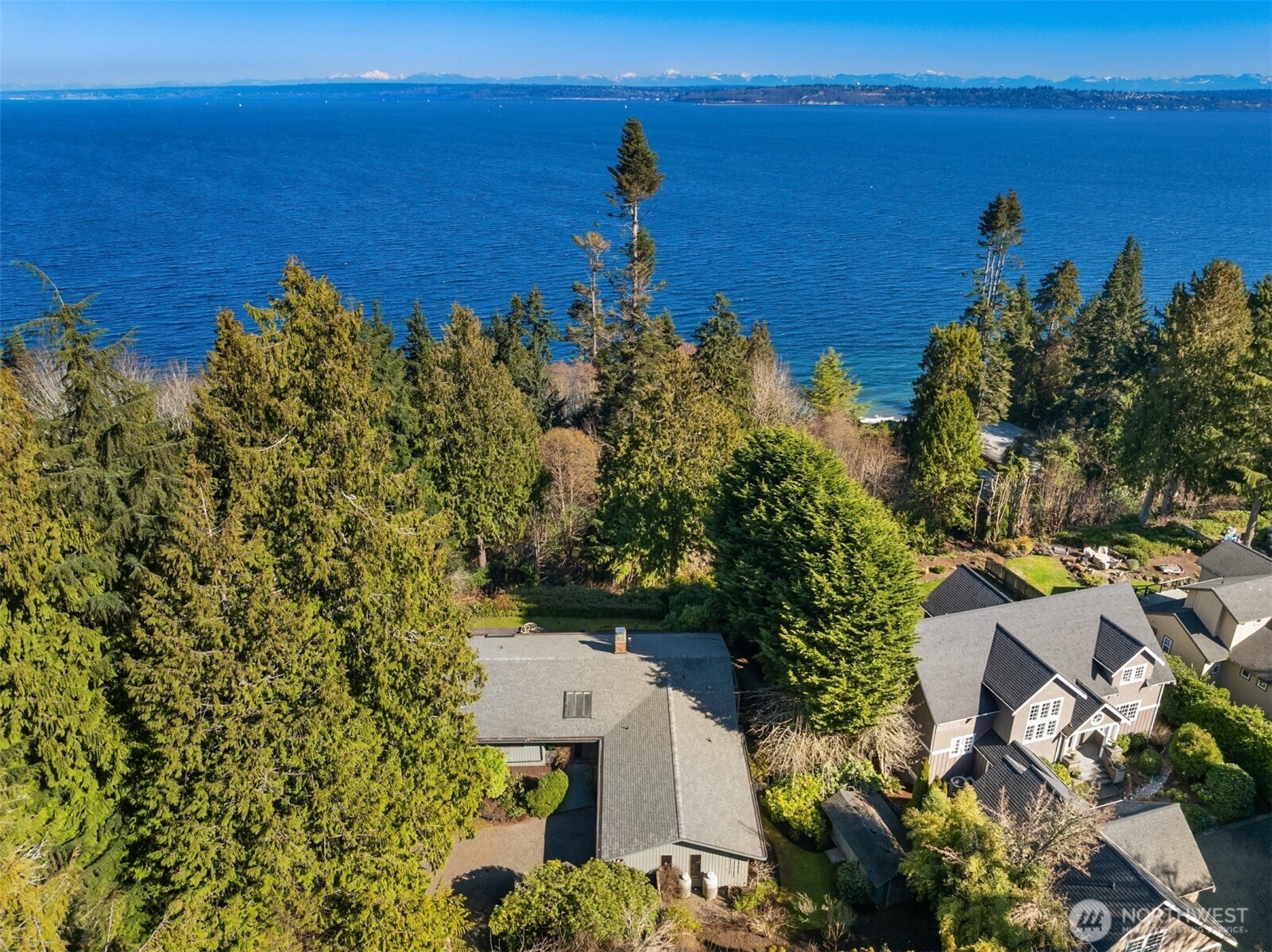 Tucked within a private waterfront neighborhood in the Wing Point community, this rare rambler offers an exceptional blend of privacy, scenery & everyday ease— all just moments from DT Winslow and the Seattle ferry. Surrounded by nearby parks, beach accesses & miles of walking & biking routes, the coveted island lifestyle is celebrated daily. Spanning 2 separate half-acre parcels, the property feels both expansive & secluded. Established landscaping frames a sun-filled yard, while the forward parcel preserves views across Puget Sound to the Cascade Mountains, with subtle glimpses of the Seattle skyline. A defining feature is the towering evergreen w/a generational eagle’s nest, where the spread lives and returns, again & again. Inside, the home is spacious & thoughtfully oriented to capture the views. A classic single-level layout offers safety & ease, w/light-filled gathering spaces & large windows & sliders that draw in the surroundings. A full-length view deck encourages a natural indoor-outdoor connection. The generous kitchen features ample cabinetry & workspace, flowing easily into the breakfast nook, dining area & family room. 3 bedrooms include a primary suite w/direct deck access & beautiful views. Attached 2-car garage & extra parking accommodate a boat, RV, or guests. Move-in ready w/ stylish appeal, this home also offers the opportunity to elevate & personalize over time. A picture-perfect setting paired w/enduring quality & potential— a truly special offering.