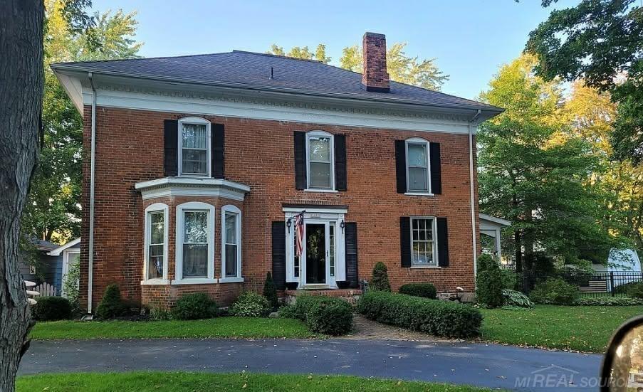HISTORIC FEDERAL-STYLE BRICK HOME IN THE VILLAGE - Spacious 2800+ sq ft home with tons of possibilities. 5/6 Bedrooms, 3 baths, LR with built in bookcase, wet bar and window seat, formal dining room, den/family room, plank and hardwood floors and original touches throughout. Lovely covered porch on the south, deck on the North side. Beautifully landscaped fenced yard. Over sized garage. Access to Lake Huron at the end of Lake Street.  No Sign on property