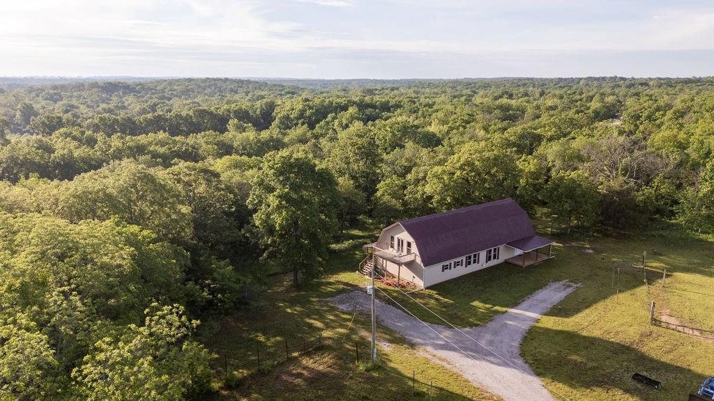 Nestled against mature oaks on 6 acres with nearly 4,000 square feet of space, this home is a dream come true for anyone wanting to get out of the city. Quietly located at the end of a county road, yet close enough to Nevada and El Dorado Springs making grocery runs a breeze. With 6 acres you will have plenty of room for gardens and the current outbuildings provide cover for lawnmowers, tractors, and even a couple of dozen chickens if you desire. The oversize front yard is fenced providing enough pasture for horses and livestock. Inside the home, you are greeted with wood floors, oak cabinets, and a Harman pellet stove, all together making the large living space feel cozy and warm. The open kitchen is equipped with quartz countertops, an electric range, two ovens, a fridge/freezer, along with an extra-large freezer in the utility room. The enclosed sunroom and large open deck are the perfect spot for morning coffee as you listen to the bobwhite quail singing their song and reminding you of the peace and serenity this place provides. Across from the kitchen is the first room with a half bath just across the hallway. At the end of the hall, you are greeted with two bedrooms with large walk-in closets and a shared full bath. Upstairs, the second floor consists of 2 rooms, a large closet, and an oversized full bath, making this a great place for kids, guests, or even a game room. Double doors lead to a deck with stunning views of the open fields and the best opportunity to catch that perfect sunset after a long day.