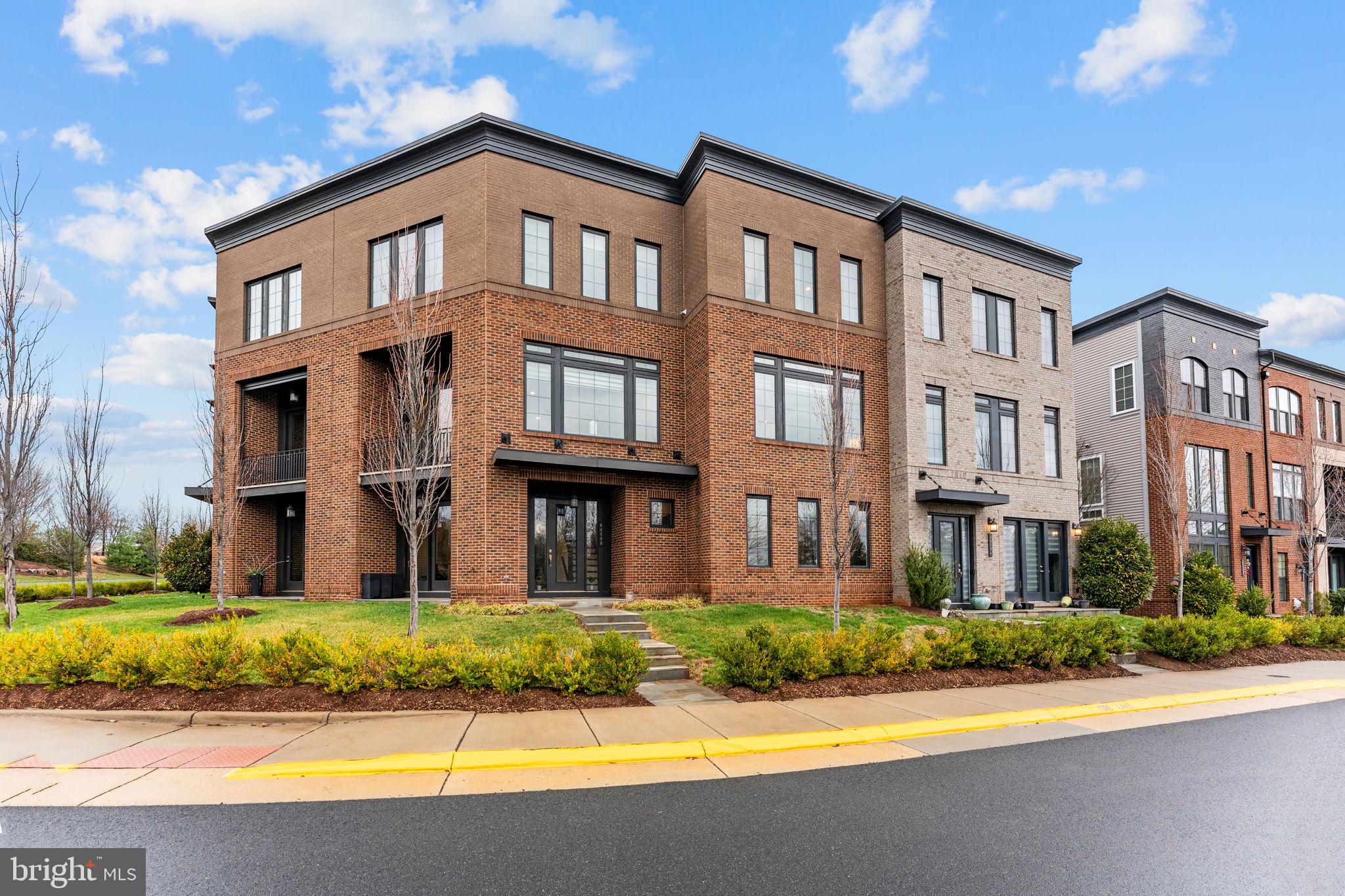 Welcome to 23132 Brooksbank Square, a beautifully designed Belgrave floorplan by Miller & Smith, built in 2018 and offering over 3,100 square feet of stylish, flexible living in the heart of Brambleton’s sought-after Garden District.With architecture reminiscent of a classic New York brownstone, this three-level townhome blends timeless charm with modern functionality. Inside, you’ll find two spacious primary suites, an additional bedroom or office, three full bathrooms, and two half bathrooms—thoughtfully designed to accommodate today’s dynamic lifestyles.The main level features a bright, open-concept layout with seamless flow between the living, dining, and kitchen spaces—ideal for both everyday living and entertaining. Just off the kitchen, step out onto your private deck, perfect for morning coffee or summer barbecues.Upstairs, the home truly shines with two primary suites on the third level, each offering generous space and en-suite baths—creating a rare and versatile retreat ideal for guests, multi-generational living, or dual home offices.The lower level provides additional living space perfect for a recreation room, home gym, or office, while the two-car garage and low-maintenance lifestyle make daily living effortless. The HOA handles lawn care, and Verizon internet is included, offering both convenience and value.Located in Brambleton’s Garden District, you’ll enjoy beautifully maintained trails with lush landscaping and greenery right outside your door. The community offers over 18 miles of paved trails that thoughtfully pass under roads for uninterrupted access, connecting neighborhoods, parks, and the vibrant Brambleton Town Center.At the Town Center, you’ll find shops, restaurants, Harris Teeter, and a beloved Sunday farmers market. Residents also enjoy access to five outdoor pools, community centers available for private events, sports courts including basketball, pickleball, and tennis, as well as stocked ponds for recreational fishing.This is more than a home—it’s a lifestyle rooted in connection, convenience, and elevated everyday living.