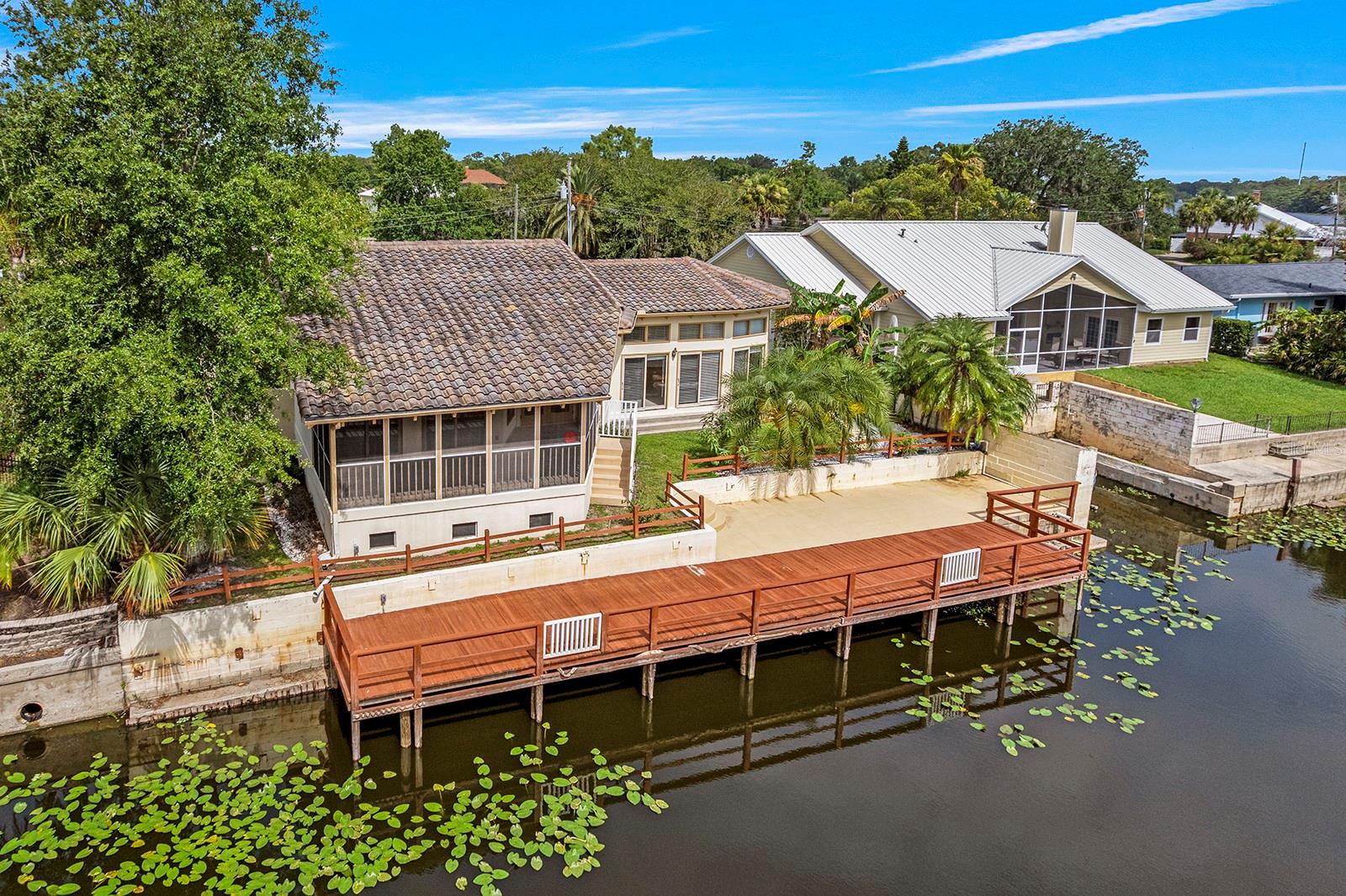 Embrace the beauty and peace of living in a small neighborhood on the water.  St. Johns River Estates was built in the early 1970's along 3 canals, each about a block long, connected to the St. Johns River.  Originally built in 1972, this home was re-designed and re-built in 1992 by Orlando architect, Allen Arthur.  The front two bedrooms and bath, as well as the kitchen were retained and the new living space is up 3 steps, with the primary bedroom suite and screened porch up 3 more steps.  Built to bring the outside in, the STUNNING REATROOM features a soaring, WHITE BEAMED, WOOD CEILING and 10 FLOOR TO CEILING WINDOWS.  Completing the space is MARBLE TILE flooring and a WET BAR accented with imported Italian tiles.  What a place to have a party! The primary bedroom is offers a view to the River and access to the screened porch. Its wood ceiling is an echo from the greatroom with its white beams. The ensuite bath is spacious with a big walk-in closet.  Also on this level is the large screened porch, a lovely space cantilevered from the home toward the water and featuring a vaulted ceiling, lighting and fans.  You will definitely be spending time here to enjoy the sights and sounds of nature.  Exiting the screen porch brings you a LOVELY PAVED PATIO AND 65 FOOT DOCK along the canal.  New pilings were installed in 2021 and the concrete seawall is in good shape.  The original part of the home was completely remodeled in 2023.  Wood flooring was installed in both bedrooms and the bathroom was re-done with high grade tile and fixtures. The kitchen was also remodeled with solid wood cabinetry, soft close drawers, under cabinet lighting, tile backsplash, quartz countertops and stainless steel appliances.  On either side of the home is a private patio, perfect for quiet time or container gardening.  The laundry room includes newer appliances.  At the rear of the garage is a delightful 6 x 17 foot HOBBY/WORKROOM, complete with cabinets, a sink, lighting and a window. Other upgrades to the property are the commercial grade GENERATOR and whole house WATER PURIFICATION system.  There is an abundance of storage available in this home, including 3 attics, large closets and extra cabinetry in the laundry room, hobby room and garage.  Make an appointment to see this special home TODAY.