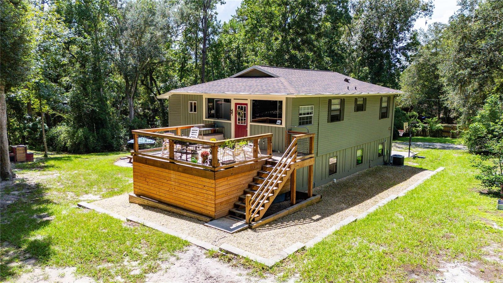 Some homes offer more than a place to live. They offer the life you have been dreaming about. Welcome to 24142 Tamber Road, a remarkable five-acre country retreat in Brooksville’s scenic Spring Lake area, where rolling hills, mature trees and breathtaking views have earned this countryside its nickname: the “mountains of Florida.” Frequent sightings of deer, wild turkeys and other native wildlife add to the peaceful, storybook setting.Originally built in 1993, this five-bedroom, three-bath farmhouse was extensively remodeled and expanded in 2024, giving it the comfort and feel of practically new construction while preserving the warmth and character of a true country home. Major improvements include a new roof, fresh interior and exterior paint, extensive storage and thoughtfully selected finishes throughout. Wood-look tile flooring complements the first floor, while laminate plank flooring continues throughout the second level, with 6-inch floor trim throughout the entire home. Board and batten, shiplap, beautiful built-ins and farmhouse-inspired details bring character to every room.The spacious lower level features four bedrooms, a large bathroom and an impressive great room, creating plenty of flexibility for guests, multigenerational living, recreation, homeschooling, hobbies or working from home. Upstairs, the inviting main living level welcomes you through the front door just off the expansive wood deck. The open floor plan brings the kitchen, dining and living spaces together, making it equally suited for comfortable everyday living and memorable gatherings. The breakfast nook can be flexible as a game room or lounging area. The beautifully designed primary retreat offers privacy, double closets and a peaceful place to unwind. A versatile Midea convertible refrigerator provides additional convenience and flexibility for food storage.Outside, the property is designed for enjoying the Florida countryside. Relax or entertain on the expansive wood deck, explore the creek, raise chickens in the established coop or bring your animals and homesteading dreams. An outdoor sink and shower make cleanup easy after gardening, working with animals or spending the day exploring the property. Mature trees provide beauty, shade and privacy, while a new retaining wall and French drain system help direct water away from the home.This is the kind of place where lasting memories are made; watching wildlife cross the property, exploring beneath the trees and enjoying the freedom that comes with five acres of your own. Peaceful and private yet connected to Brooksville’s welcoming community and small-town charm, this extraordinary property offers room to breathe, freedom to grow and the country lifestyle so many are searching for.