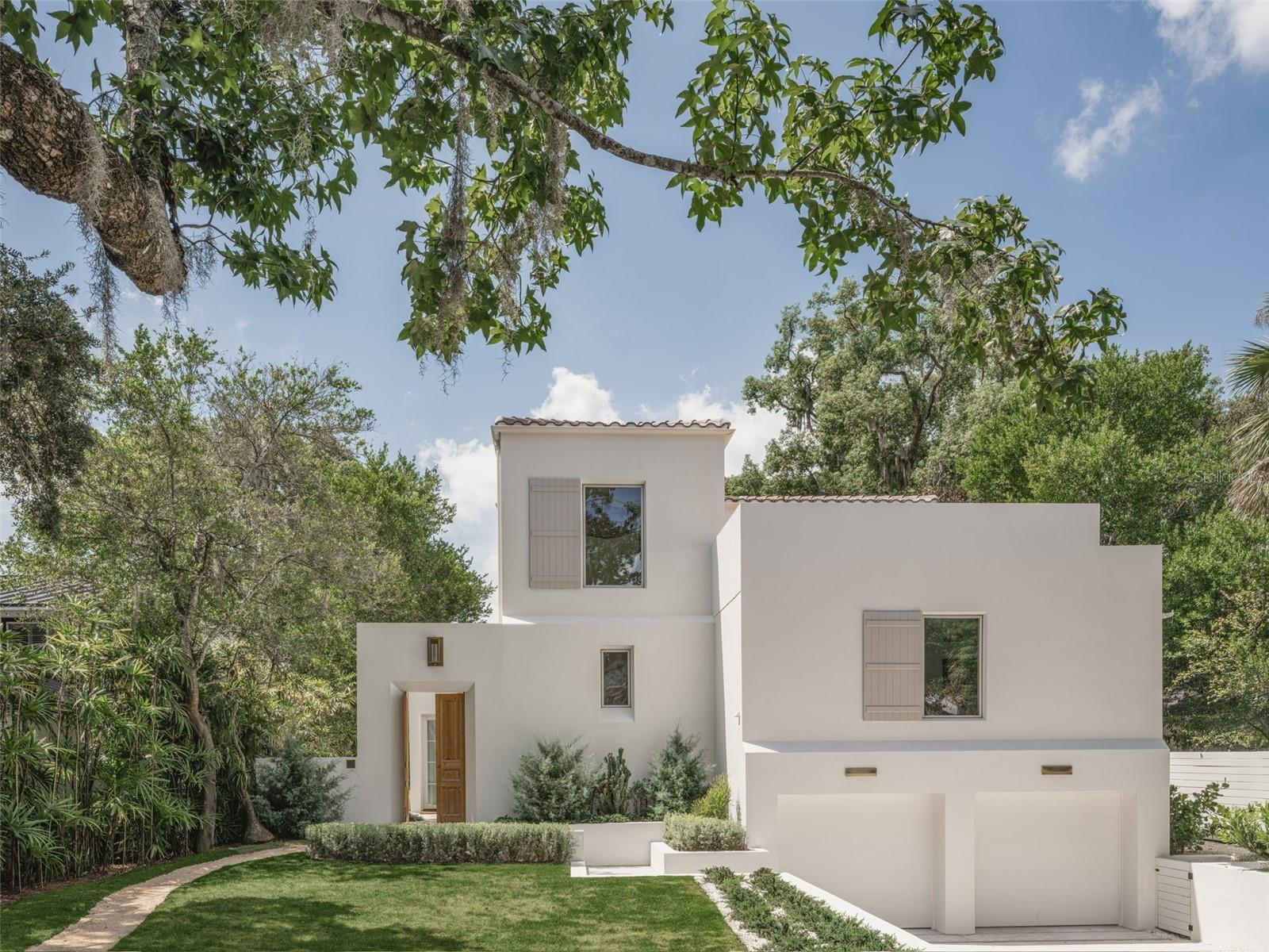 In the heart of Winter Park, 1150 Via Salerno is a newly completed Mediterranean-minimalist residence that blends architectural refinement w/ organic warmth. Now offered at a newly adjusted price, the home presents a compelling opportunity to experience design-forward new construction in the Vias neighborhood. Developed and designed by Steve & Jodie Warrick Konold of Scout & Co., the 3,850-sf layout offers 4 bedrooms & 5.5 baths, wrapped in the intentional privacy of a luxury retreat. Beyond its terraced walkway & garden courtyard—envisioned in collaboration w/ architect Cynde Norris—French antique gates open to a native-planted entry garden, creating a soft transition to the interior. A glass foyer introduces a tongue-and-groove ceiling & woven rattan chandelier, sourced & designed in London, leading to a sculptural stairwell positioned just off the main living spaces. The great room features soaring ceilings, a sleek fireplace & walls of glass windows & doors that blur the boundary between inside & out. Ten-inch baseboards meet level 5 drywall in a clean reveal, paired w/ micro-crete flooring on the main level & wide-plank European oak upstairs. In the kitchen, materials w/ function are elevated w/ a Thermadore dual-fuel range, custom plaster hood, full refrigerator & freezer columns & a large island topped in honed black quartzite. The surrounding cabinetry is crafted from hand-carved V-groove panels w/ soft-close hardware & integrated pullout storage. Caesarstone surfaces run along the perimeter while steel-and-glass open shelving w/ a sculptural black sconce balance the composition. A vintage chandelier from Prize Home & Garden sourced in Round Top completes the room. The primary suite occupies a private wing on the main floor accessed via antique gallery doors that lead to the rear courtyard. Vaulted ceilings, a custom walk-in closet w/ a spa-like bath provide a luxurious retreat. Features include a long double vanity, matte black Kohler fixtures, a freestanding tub, walk-in shower w/ built-in bench & separate water closet. On the mezzanine level, the powder bath makes a dramatic statement w/ a floating black quartzite trough sink w/ handwoven mirror. Across the hall, the laundry room blends beauty w/ utility w/ custom cabinetry, matching quartzite surfaces, matte black fixtures & a side-by-side front-load washer & dryer. A nearby guest suite is marked by an antique door entry. The en-suite bath features a hand-painted tile threshold & suede-framed mirror. Two upstairs bedroom suites feature en-suite baths, designer lighting, distinctive mirrors & continuous European oak flooring. Positioned at the front of the home, the rooftop terrace is accessible via the upper hallway. The detached casita opens to the pool courtyard through accordion glass doors & features micro-crete floors, a woven rattan chandelier & a full bath—ideal as a studio, gym or office. Outdoor spaces include two garden courtyards, a fully fenced backyard, a heated saltwater pool & a rooftop terrace, all enclosed by masonry walls & a board-on-board privacy fence. Additional features include a lower-level two-car garage, storage closet, 3 HVAC systems, Rinnai tankless water heater, Sierra Pacific windows, customized closets, solid core interior doors, 6” round gutters & a Barcelona barrel tile roof. Thoughtfully designed & beautifully executed, 1150 Via Salerno offers a refined lifestyle tucked within one of Winter Park’s most exclusive enclaves.