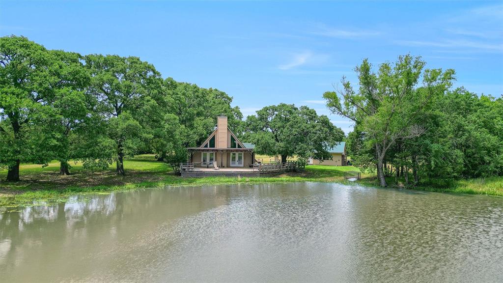 Discover the perfect blend of privacy, recreation, and opportunity located minutes from Lake Texoma! This beautiful property offers wide-open Texas land and a peaceful setting ideal for those looking to escape the city, build a private retreat, or invest in acreage with future potential. Outdoor enthusiasts will appreciate the excellent hunting and fishing opportunities, making this an ideal property for a weekend getaway, recreational ranch, or full-time country residence. With plenty of room to roam and enjoy the outdoors. Adding to its investment appeal, the land can be subdivided, providing flexibility for future development, multiple homesites, or the opportunity to sell individual parcels. Nestled among a variety of mature trees and two ponds, the property features a charming A-frame home with an open-concept floor plan designed for comfortable country living. A wood-burning fireplace creates a warm and inviting centerpiece for the main living area, perfect for relaxing after a day spent outdoors. One of the highlights of the home is the large deck that wraps around approximately half of the house and overlooks the ponds. Step outside, cast a line, and fish right from the deck, or simply sit back and enjoy the peaceful surroundings and beautiful views. The property also includes a two-car covered carport and an attached workshop, offering convenient covered parking along with valuable space for tools, equipment, hobbies, or outdoor gear. Whether you're searching for a hunting and fishing property, recreational land, a private homesite, or an investment opportunity, 263 Rio Roxo Road offers versatility and the freedom to make it your own.