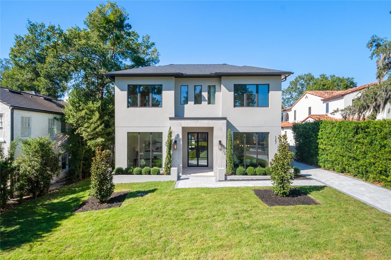Nestled just moments from the boutiques and cafés on Park Avenue, this newly completed masterpiece redefines Winter Park luxury living. Perfectly positioned on an expansive 0.30-acre lot, this residence captures attention from the moment you arrive, with its striking architectural details, a sweeping driveway, and detached garage that together set a tone of timeless sophistication. Inside, soaring 20-foot ceilings welcome you into a grand foyer framed by curved archways and exceptional millwork. The living room is a true showpiece, centered around a statement fireplace with built-in shelving and subtle LED underlighting that accentuates every detail. The chef’s kitchen is a work of art, showcasing quartz countertops, exquisite custom cabinetry, integrated LED lighting, a Wolf appliance suite, and a charming breakfast nook. The formal dining room captivates, with stunning coffered ceilings floor to ceiling windows, and an atmosphere perfectly suited for elegant entertainment. The primary suite is a private sanctuary, offering dual vanities with floating mirrors, a freestanding soaking tub, a walk-in rain shower, and a spacious custom closet. Each additional bedroom has been thoughtfully designed with generous proportions and its own en-suite bath, blending comfort with sophistication. Upstairs, a loft and secondary laundry area provide convenience and versatility, while the main level includes a full mudroom and butler’s pantry with an additional washer and dryer, tailored for effortless living. The outdoor living space rivals the most luxurious resorts. A covered lanai with retractable screens seamlessly extends the interior’s sophistication outdoors, offering a year-round retreat for dining or lounging. The expansive pool deck unfolds around a sparkling pool and integrated spa, complemented by a dedicated pool bath connected to the detached garage. From the curved archways to the meticulous millwork and layered LED lighting throughout, every inch of this home reflects the builder’s attention to detail and commitment to craftsmanship. It is more than a home, it is a statement of style, presence, and precision in the heart of Winter Park’s most coveted location.