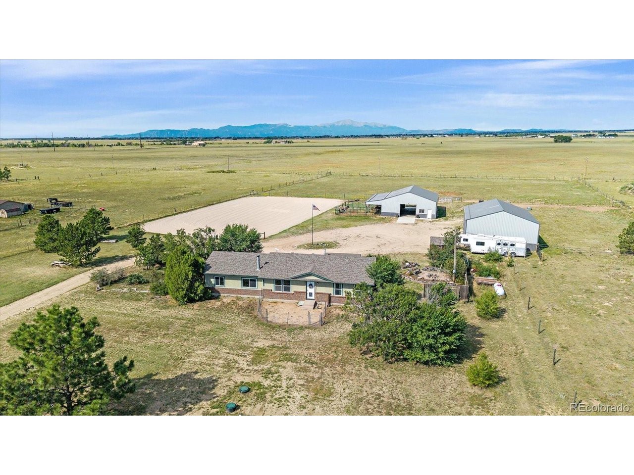Escape the city without sacrificing convenience! Set on 5 picturesque acres in Peyton, just a short commuteto Colorado Springs, this beautifully improved equestrian property pairs peaceful country living withbreathtaking Pikes Peak views. A coded security gate welcomes you to the fully fenced and cross-fencedproperty, where a circular drive surrounding a stately flagpole provides easy maneuvering for trucks,trailers, horses and equipment.The unique stick-built home offers a versatile split floorplan ideal for multi-generational living or potentialrental income. The main residence features an updated kitchen with crisp white cabinetry, granitecountertops, subway tile backsplash and eat-in dining, along with a comfortable family room, primarybedroom, full bath and additional bedroom. The lock-off suite offers a second family room with heatingstove, two bedrooms, full bath and laundry. Warm LVP flooring and updated baths create an inviting, move-in-ready feel throughout.Equestrian amenities are exceptional! The 48'x36' barn features four 12'x12' rubber-matted stalls withDutch doors, lighting and outlets, plus a wash stall, 12'x12' tack room with cabinetry and countertop,12'x12'x48' covered lean-to and three 36'x12' gated runs. A 120'x160' riding arena features concrete sandand is sloped for drainage, while three pastures/turnouts offer water and electricity along with Rammelectric fencing.Car enthusiasts, hobbyists and contractors will love the massive 48'x36' detached garage/workshop withthree 12' overhead doors, concrete floors and electrical-offering room for approximately 6-8 vehicles plusworkspace. A storage shed provides even more flexibility. Ethernet/internet and security cameras extend tothe home, barn and garage.Bring the horses, toys and Colorado dreams-this exceptional acreage property is ready for them all!