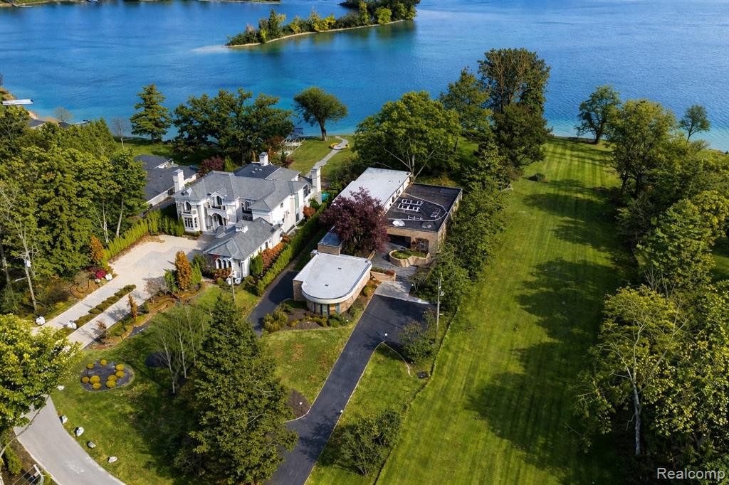 All-sports Orchard lakefront introduces this original Tobocman-designed architectural estate set on approximately 1.2 acres with nearly 100 feet of direct frontage, offering a rare indoor pool, walkout lower level, and highly sought-after first-floor primary suite, all ideally positioned near Orchard Lake Country Club. This iconic residence blends bold architectural character with expansive living spaces and seamless indoor-outdoor connectivity in one of Michigan’s most prestigious lakefront settings. The main level showcases dramatic ceiling lines, sculptural design elements, and walls of glass that capture panoramic lake views from the primary living areas. Multiple gathering spaces and a formal dining room with distinctive arched windows create an elegant yet comfortable environment for both everyday living and entertaining. The kitchen and adjacent service areas are thoughtfully designed for efficiency and functionality to support a hospitality-focused lifestyle. The walkout lower level offers an exceptional retreat highlighted by the indoor pool beneath skylit ceilings, spacious recreation and lounge areas, and direct access to the lakefront grounds. Outdoor terraces and professionally landscaped surroundings extend the living experience to the shoreline, creating ideal spaces for relaxation, entertaining, and enjoying all-sports lake living. The private first-floor primary suite features abundant natural light, terrace access, and a custom marble bath. Additional bedroom suites are positioned for comfort and privacy for family and guests. A rare opportunity to own an architecturally significant waterfront estate defined by scale, privacy, and premier positioning on Orchard Lake. Select images may include virtual staging or digital enhancements. BATVAI.