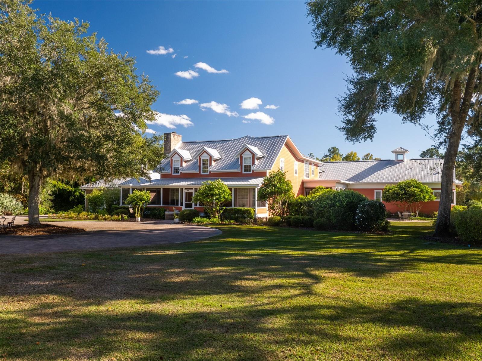 Built by Henry Ford’s great grandson as his private estate, this extraordinary 67-acre property offers a rare combination of history, privacy, natural beauty, and self-sufficient country living just minutes from Alachua and Gainesville. A gated, lamp-lined drive winds beneath rows of producing pecan trees before arriving at the nearly 6,700-square-foot main residence, surrounded by creeks, ponds, mature woods, and sweeping views in nearly every direction.Inside, the six-bedroom, five-and-a-half-bath main home is defined by remarkable scale and craftsmanship, with rare heart-of-pine floors, generous living spaces, a billiards room, bonus room, and walls of windows framing the landscape beyond. The main living room overlooks a waterfall and picturesque swimming pond, while four expansive screened porches create nearly 2,000 additional square feet of outdoor living space.The nearly 1,200-square-foot primary suite feels like a private residence of its own. Three sets of French doors open to a porch overlooking the swimming pond, while a fireplace and sitting area create an intimate retreat. Two enormous custom closets lead to an equally impressive bath with dual water closets, mahogany and marble vanities, and a matching mahogany and marble soaking tub positioned to capture extraordinary views across the creek, pond, and pecan orchard.At the heart of the home, the kitchen pairs custom cherry cabinetry with a Wolf gas range, Sub-Zero refrigeration, warming drawer, two wine chillers, dual sinks, a large island, walk-in pantry, and dedicated coffee bar.Across the swimming pond, a roughly 650-square-foot pool house and expansive decks create another exceptional destination on the property—ideal as a gym, private office, guest retreat, or transformed into a spectacular indoor/outdoor entertaining space.Continue across the bridge and through the trees to discover a secluded two-bedroom, one-and-a-half-bath guest house with its own two-stall barn. Elsewhere, an oversized climate-controlled garage, large air-conditioned bunker, and more than 5,000 square feet of covered pole barns provide exceptional space for vehicles, equipment, storage, horses, and recreational toys.The land itself is every bit as compelling as the residences. Acres of producing pecan trees provide agricultural property tax exemptions, while two natural creeks, a stocked fishing pond, open pasture, wooded acreage, and abundant wildlife create a setting that feels worlds away. Extensive solar, buried propane, a multi-thousand-gallon water tank, generator, fuel storage, and a working windmill and pump provide the infrastructure for an almost entirely self-sufficient lifestyle.In total, the estate offers eight bedrooms, seven full and two half baths across multiple structures, with extraordinary flexibility for multigenerational living, guests, recreation, equestrian use, or simply disappearing into your own private piece of Florida.All of this, just 7 minutes from downtown Alachua and approximately 10 minutes from I-75—a legacy estate with a story, scale, and sense of place that would be nearly impossible to recreate today.